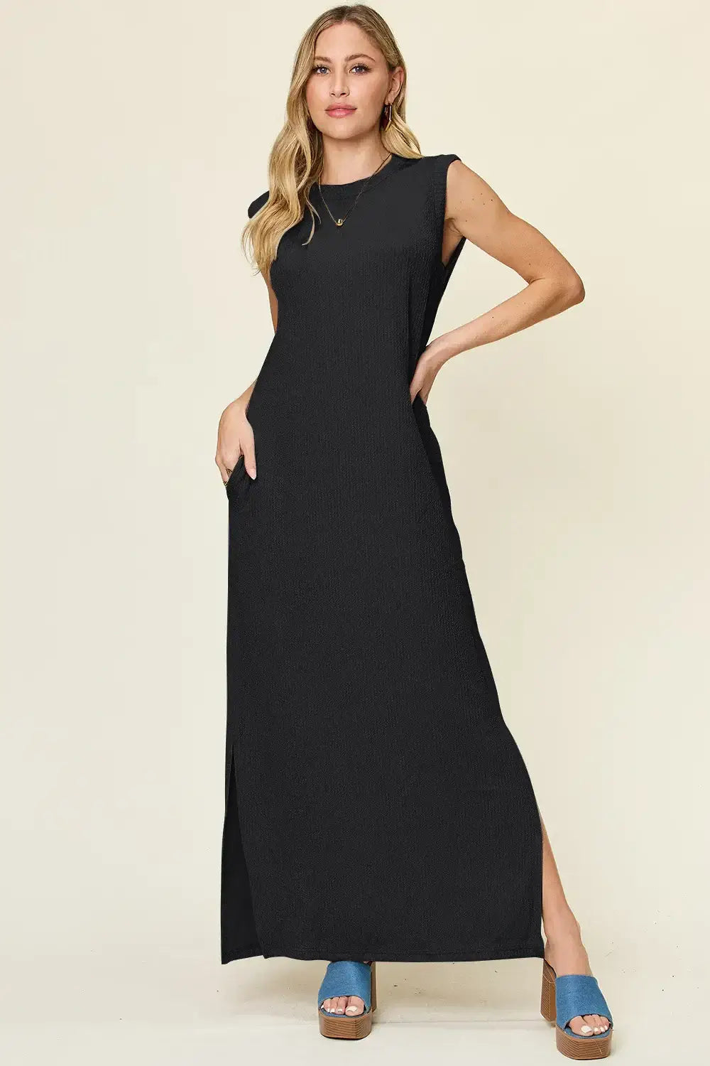 Model wearing a black sleeveless mock neck maxi dress with side slits, perfect for casual wear and stylish comfort.