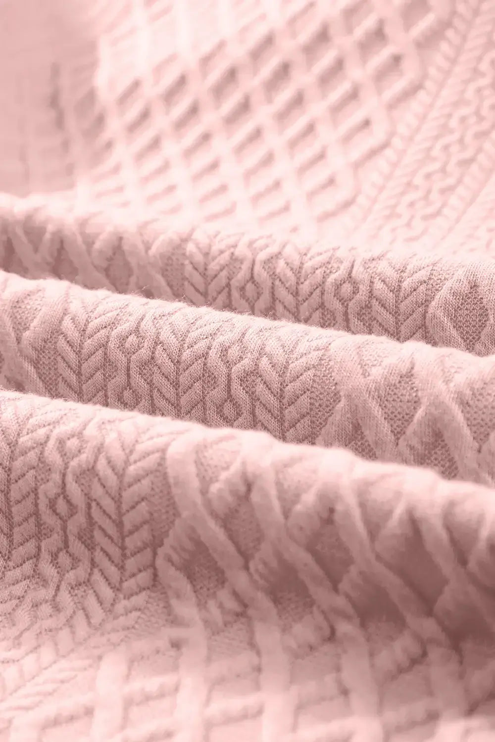 Close-up of soft pink fabric with textured patterns and subtle design details for stylish clothing.