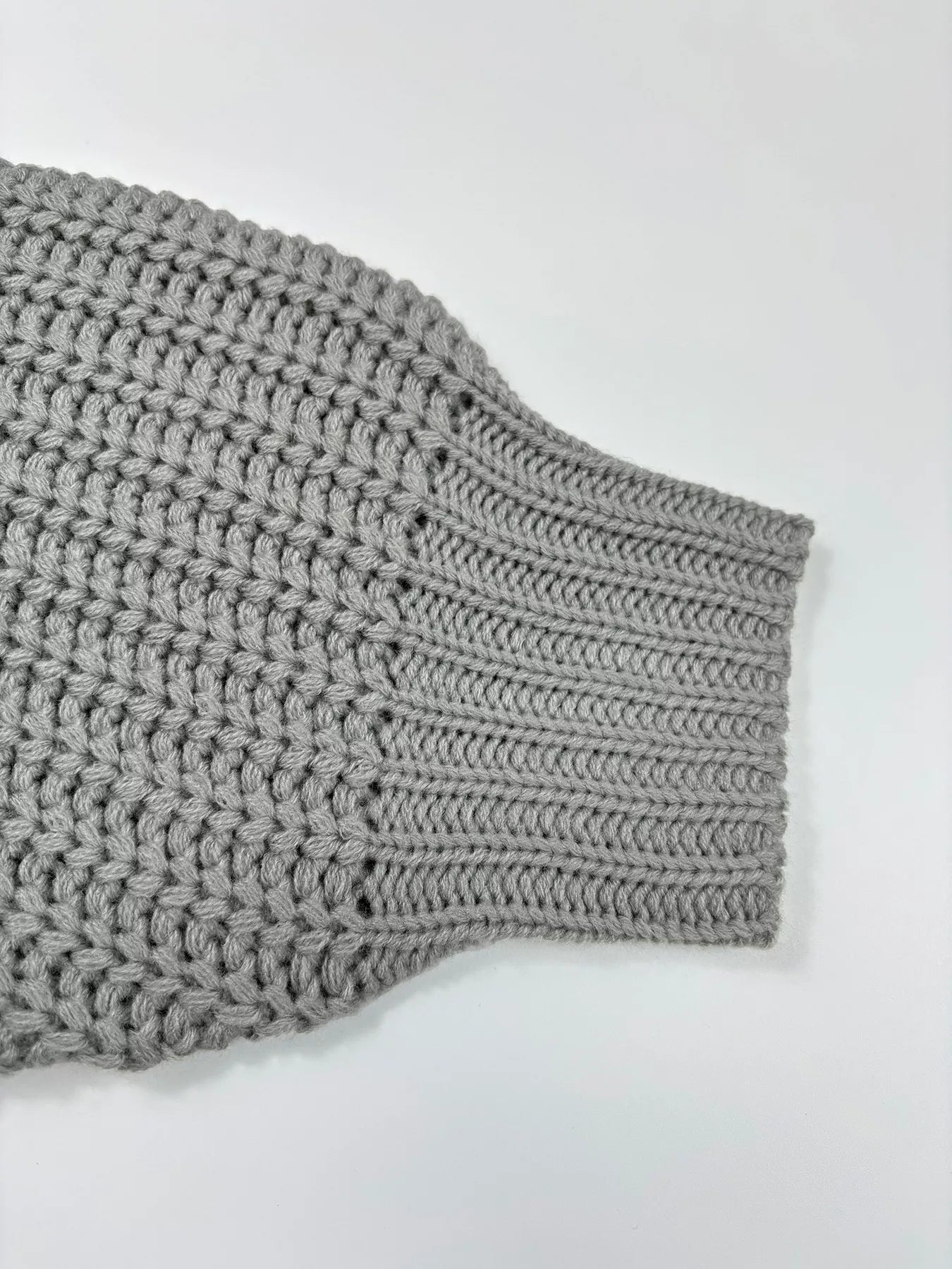 Close-up of the sleeve detail of a Chunky Knit Turtleneck Long Sleeve Sweater in gray, showcasing knitted texture.