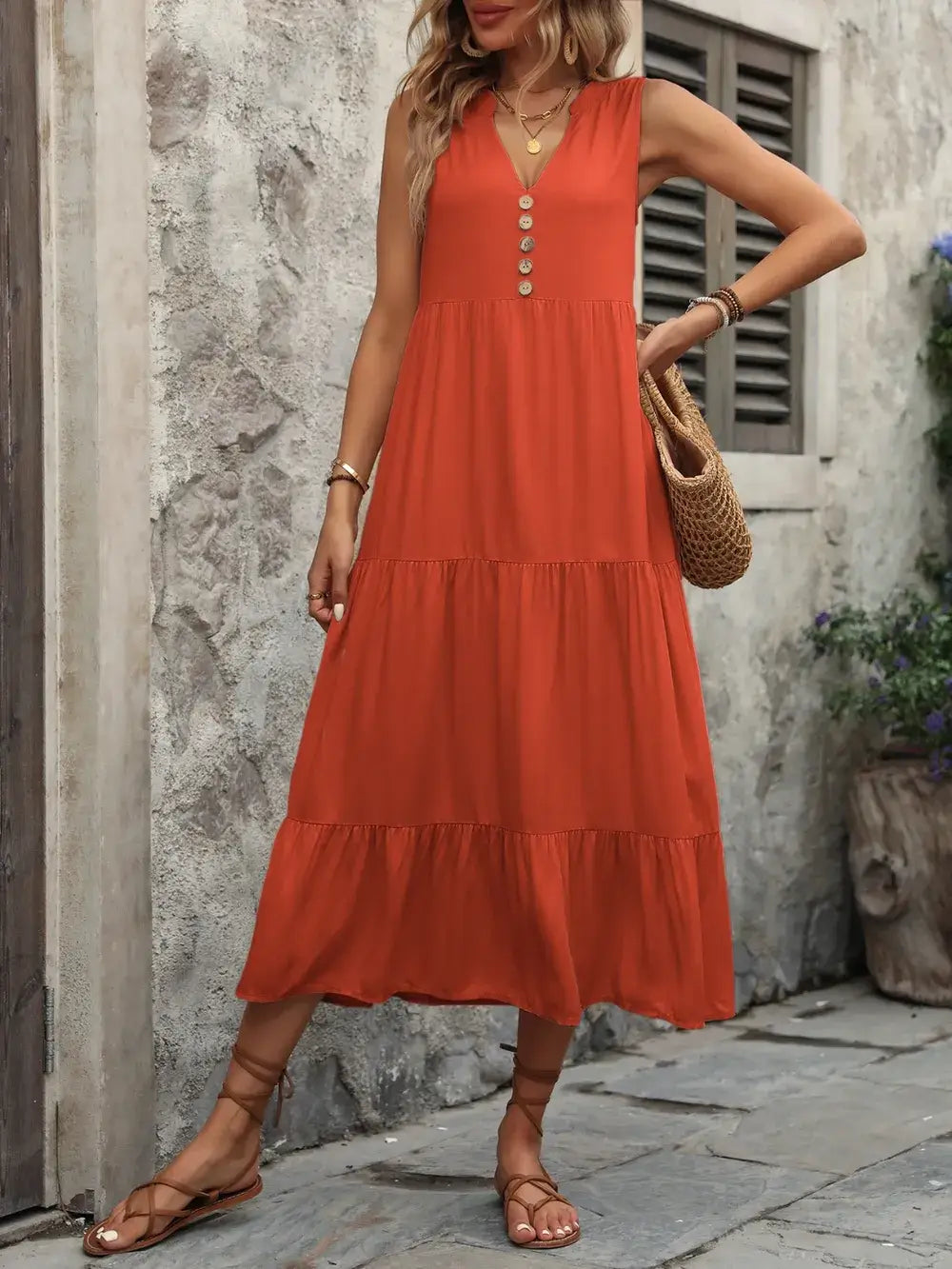 Ivy Lane Decorative Button Notched Sleeveless Dress in orange with buttons and tiered design worn outdoors.