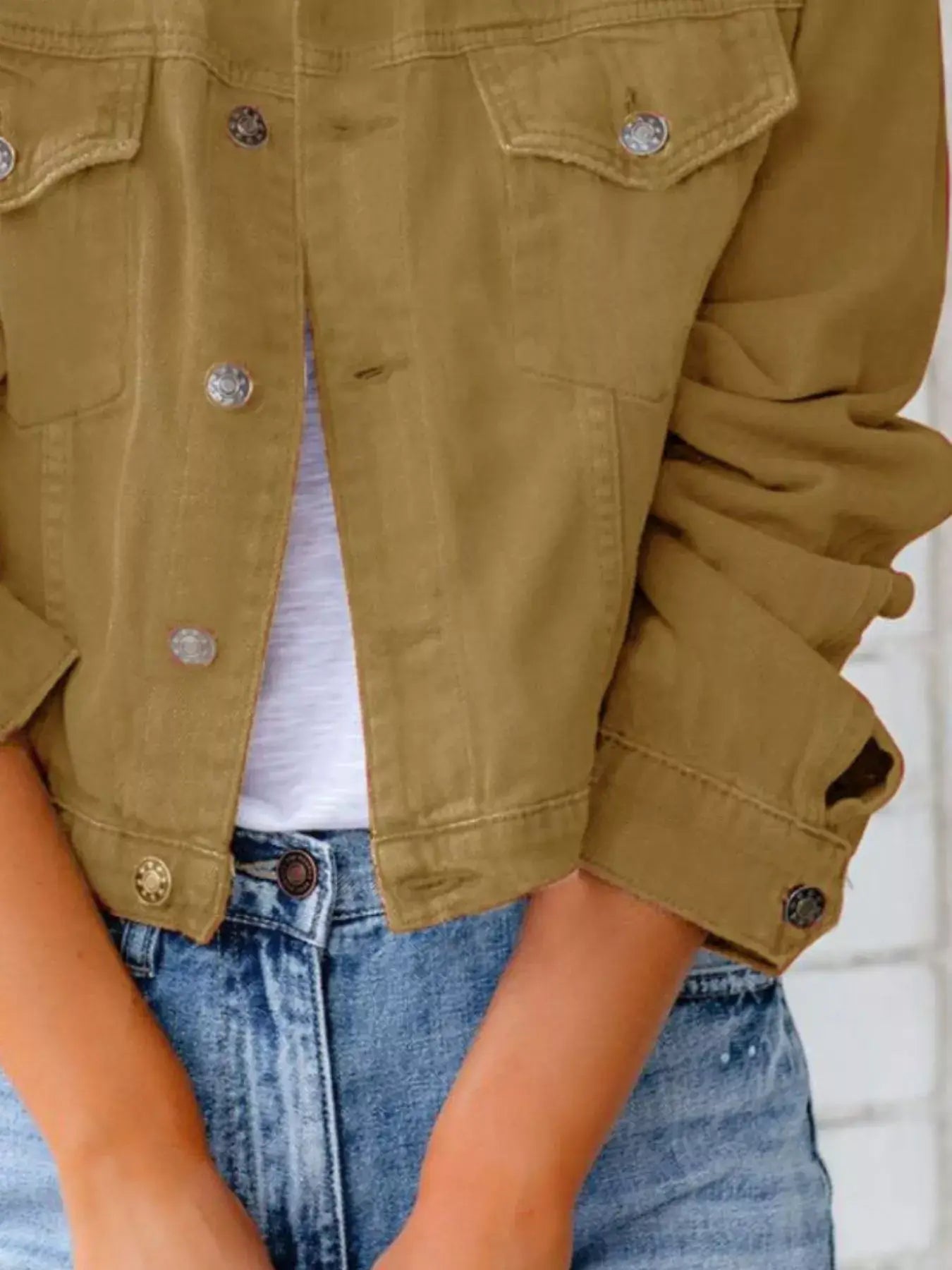 Front view of a woman wearing a button-up long sleeve denim jacket in olive green, paired with high-waisted jeans.