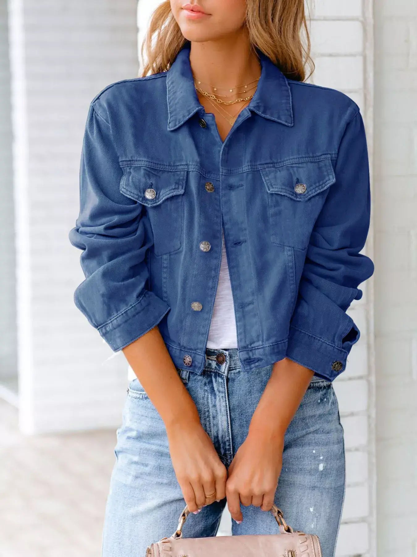 Woman wearing a button-up long sleeve denim jacket in blue over a white top, styled with casual jeans.