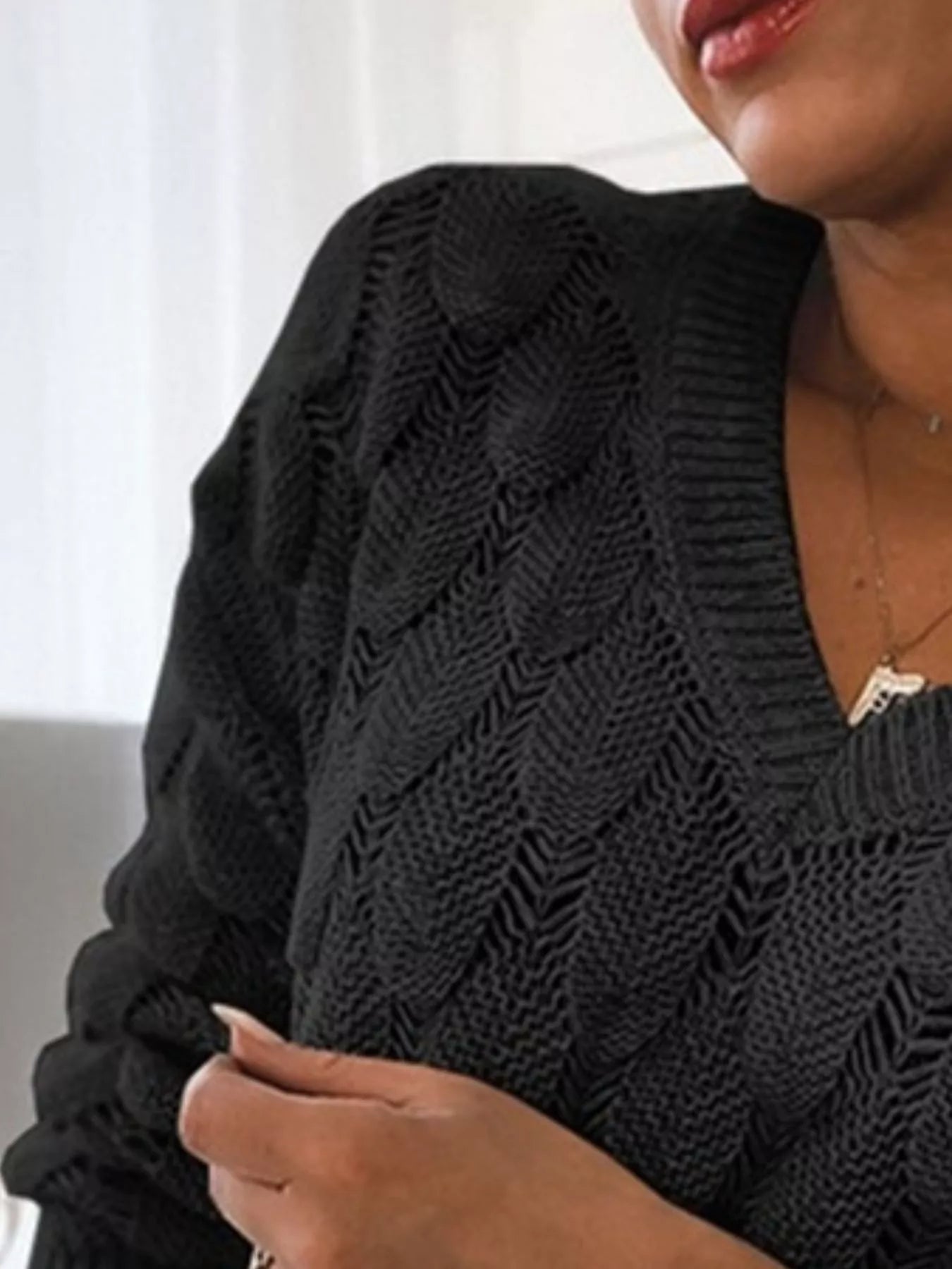 Close-up of a woman wearing a V-Neck Knitted Sweater in black, showcasing its textured openwork design.