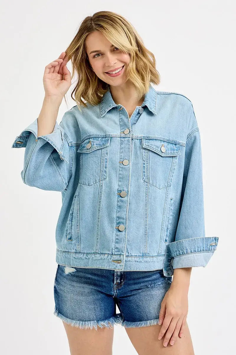 Woman wearing a RISEN Washed Dropped Shoulder Denim Jacket in light blue, styled with denim shorts for a trendy look.
