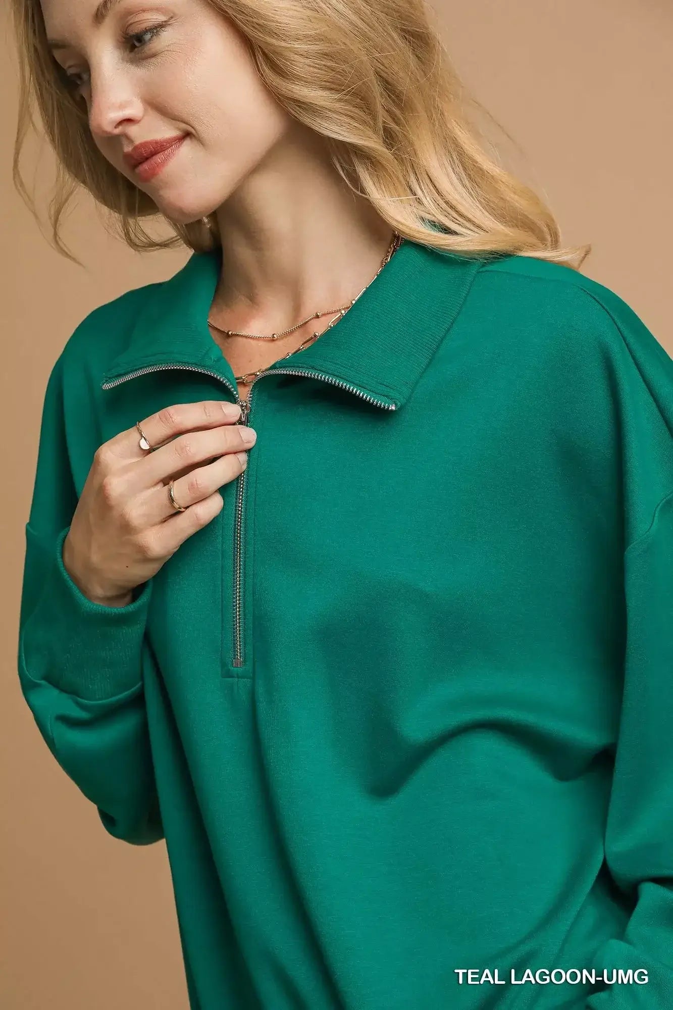 Close-up of a woman wearing the Umgee Half Zip Drop Shoulder Sweatshirt in teal lagoon, showcasing the half zip design.