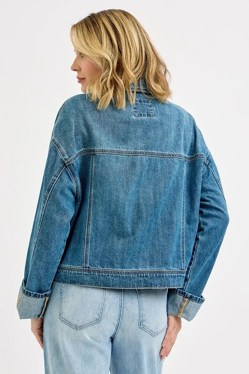 Back view of woman wearing RISEN oversized cargo denim jacket with cuffed sleeves and structured pockets.