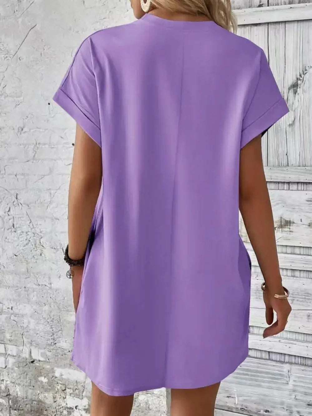 Back view of a woman wearing a pocketed round neck short sleeve dress in light purple.