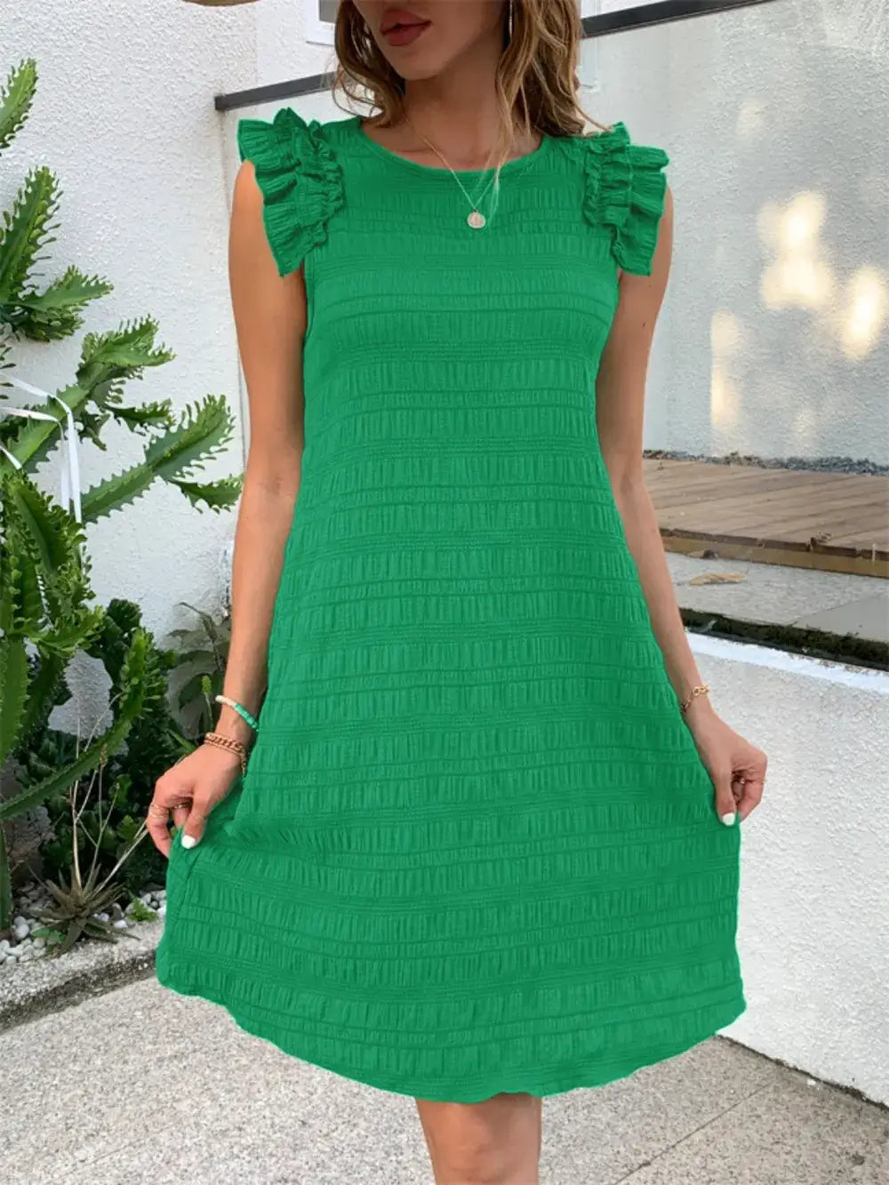 Model wearing a green ruffled round neck sleeveless dress, showcasing stylish ruffle details.