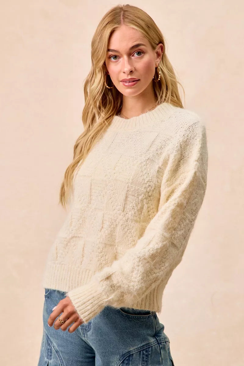 Model wearing the BiBi Checker Board Drop Shoulder Sweater in cream, showcasing its stylish relaxed fit and checkerboard texture.