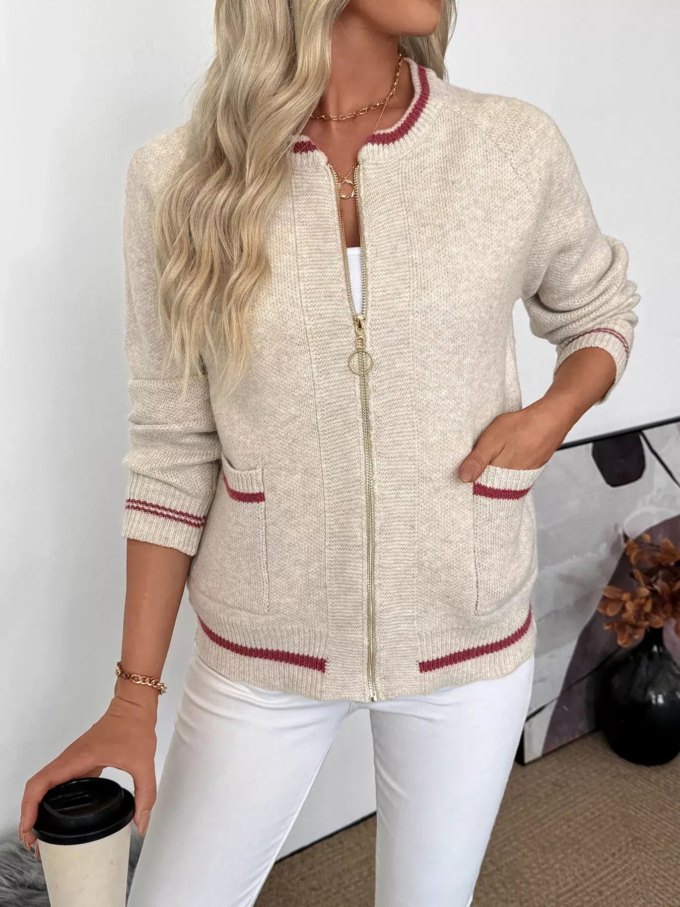 Woman wearing a Zip Up Contrast Trim Cardigan with Button Detail in beige with red trim, holding a coffee cup.