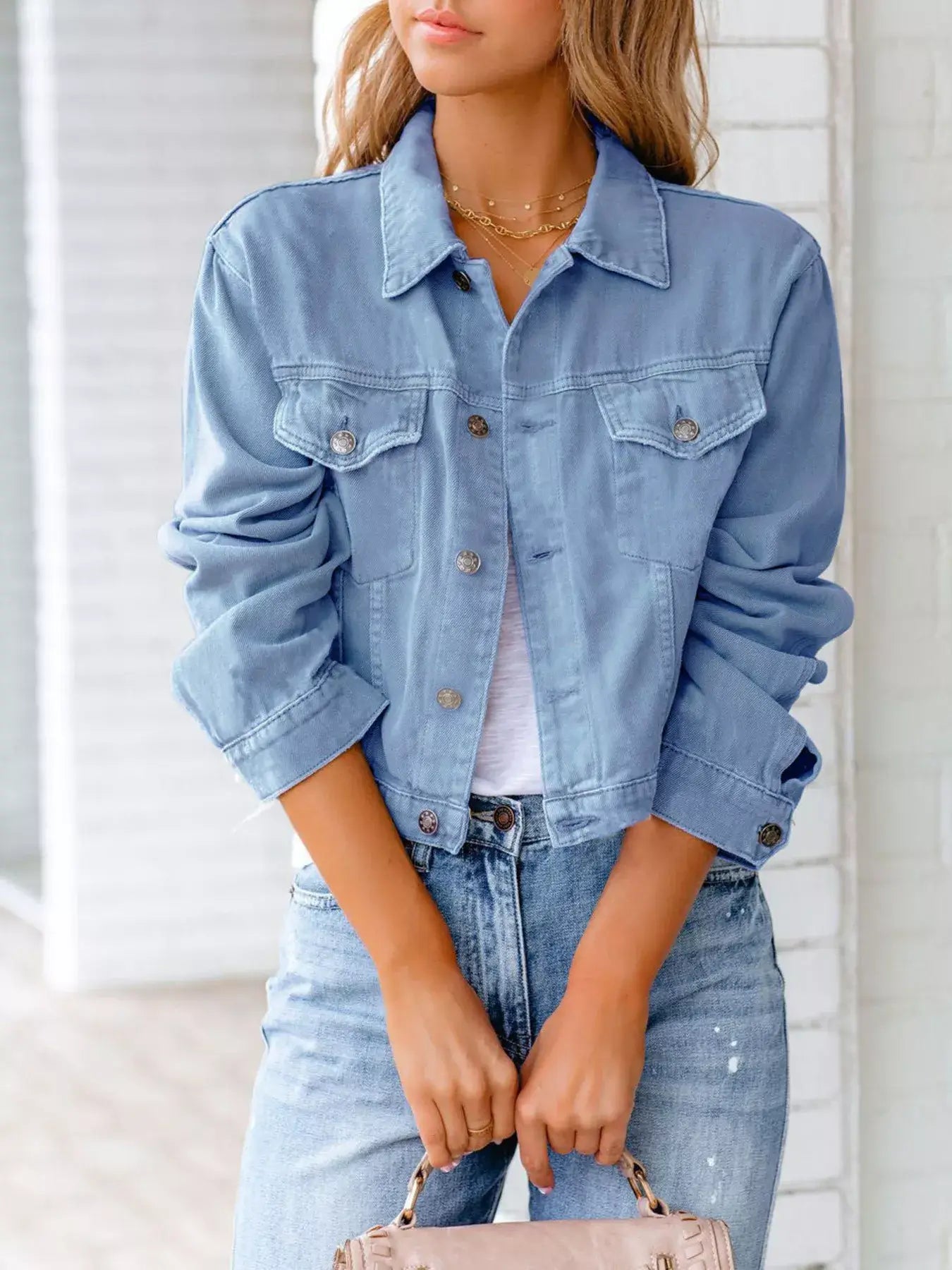 Model wearing a button-up long sleeve denim jacket paired with light jeans, showcasing a timeless and casual style.