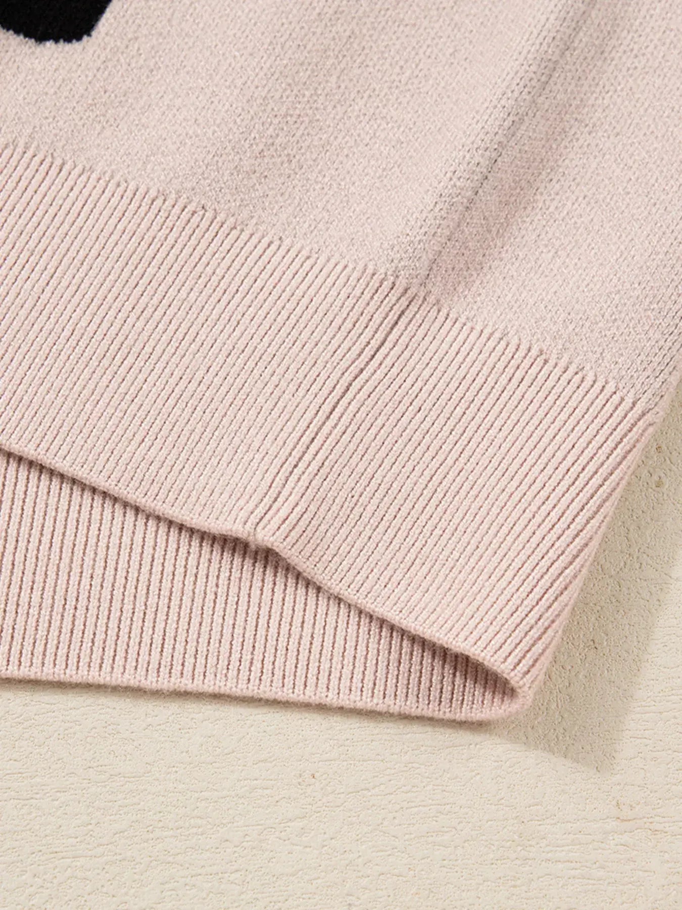 Close-up of the sleeve hem of the pearl embellished bow pattern loose sweater showcasing the knit texture.