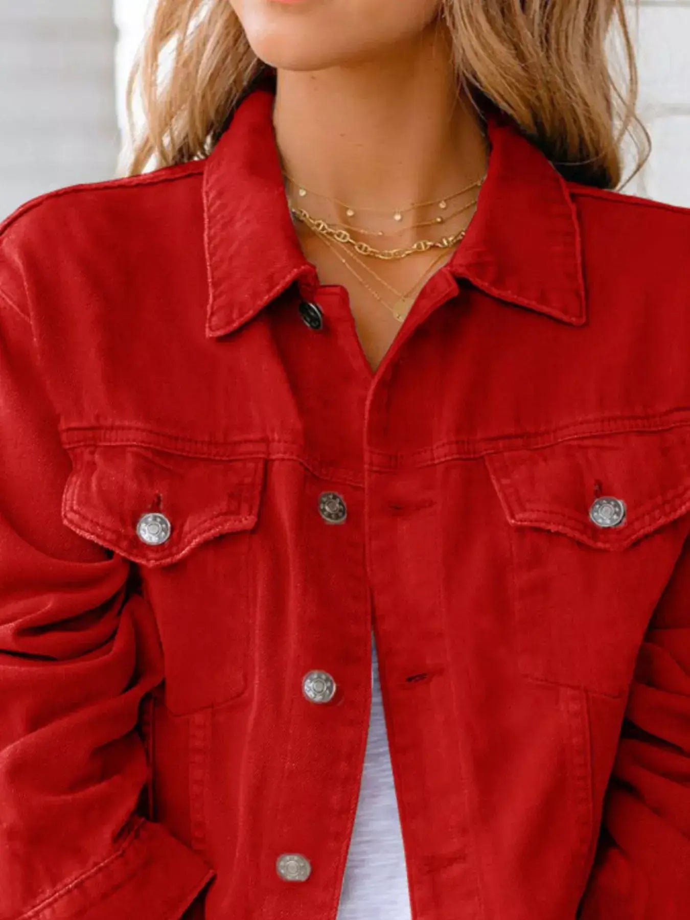 Stylish woman wearing a vibrant red button-up long sleeve denim jacket.
