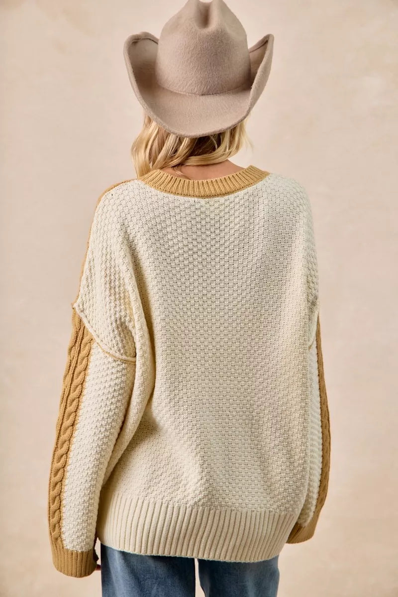 Back view of a woman wearing the BiBi Cable Knit Hacci Combo Sweater with uneven hem and a cowboy hat.