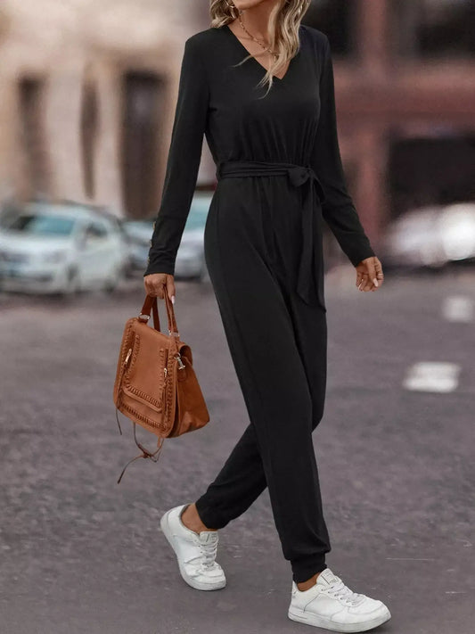 V-Neck Long Sleeve Tie Waist Jumpsuit for Women worn with white sneakers and a brown handbag on a city street.