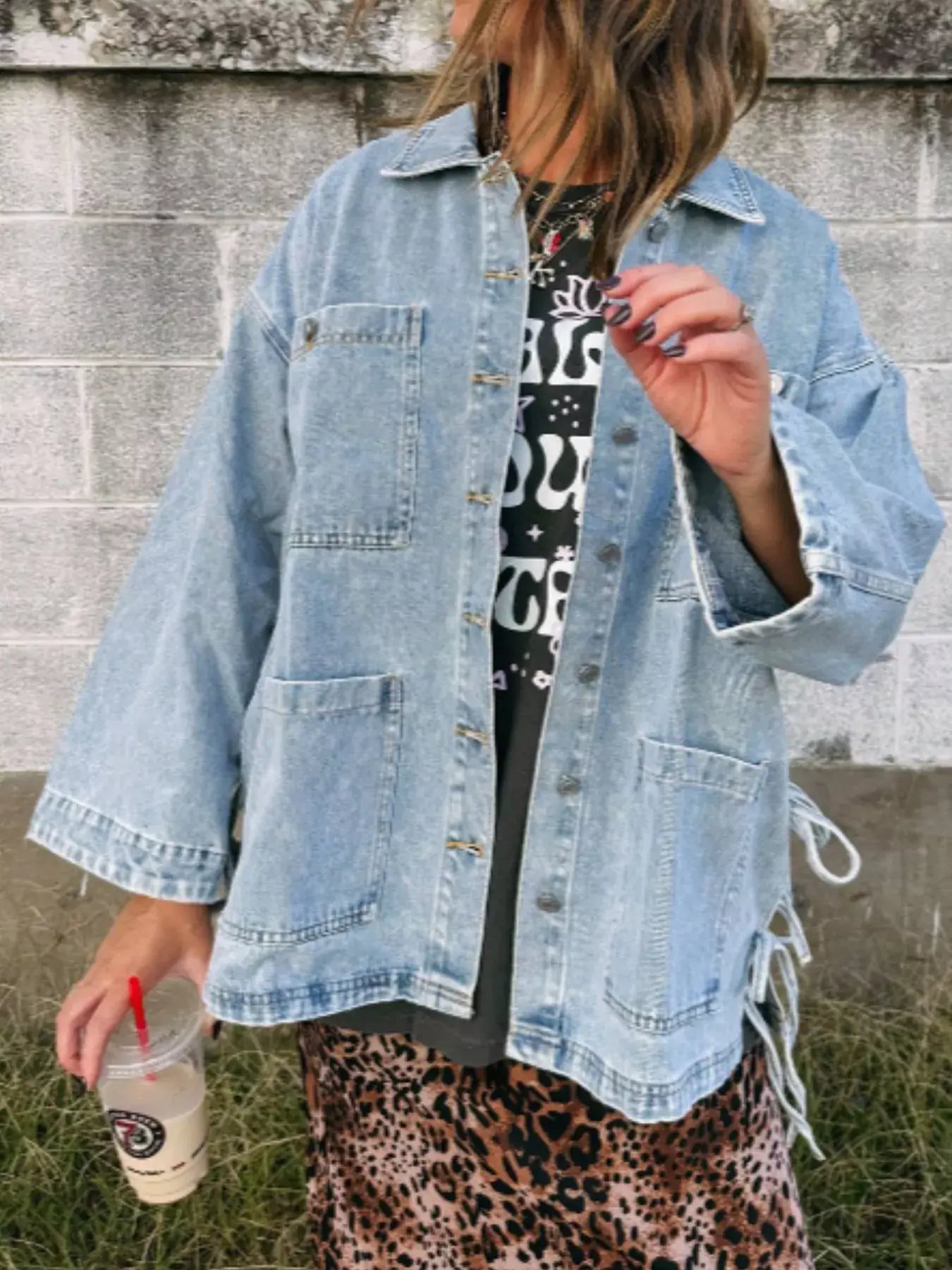 Woman wearing a Patched Pockets Side Tie Denim Jacket with oversized design, styled with a graphic tee and skirt.