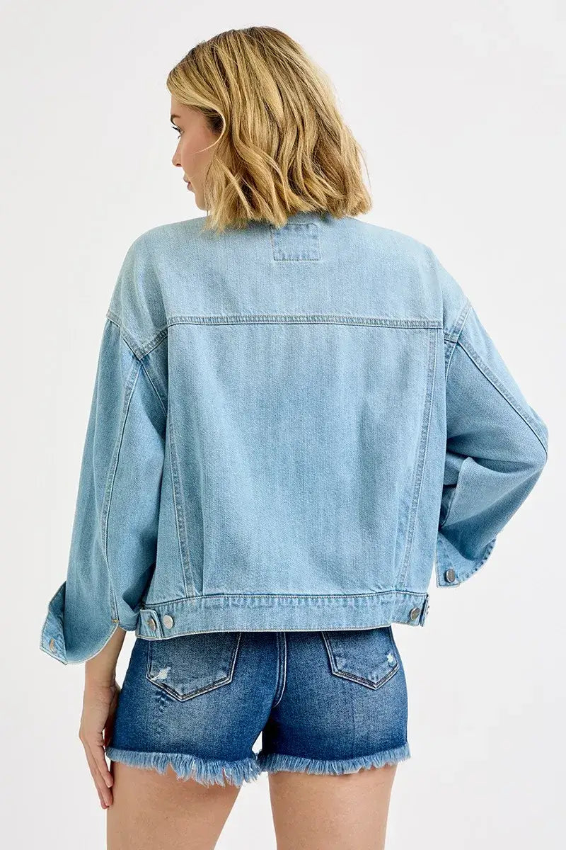 Woman wearing a RISEN Washed Dropped Shoulder Denim Jacket from the back, styled with denim shorts.