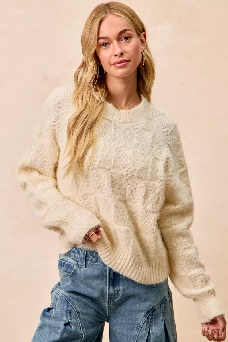 BiBi Checker Board Drop Shoulder Sweater in cream worn with casual jeans, showcasing a soft and stylish look.