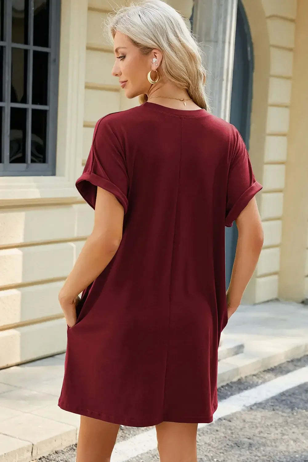 Model wearing a burgundy Round Neck Rolled Short Sleeve Tee Dress with pockets, shown from the back.