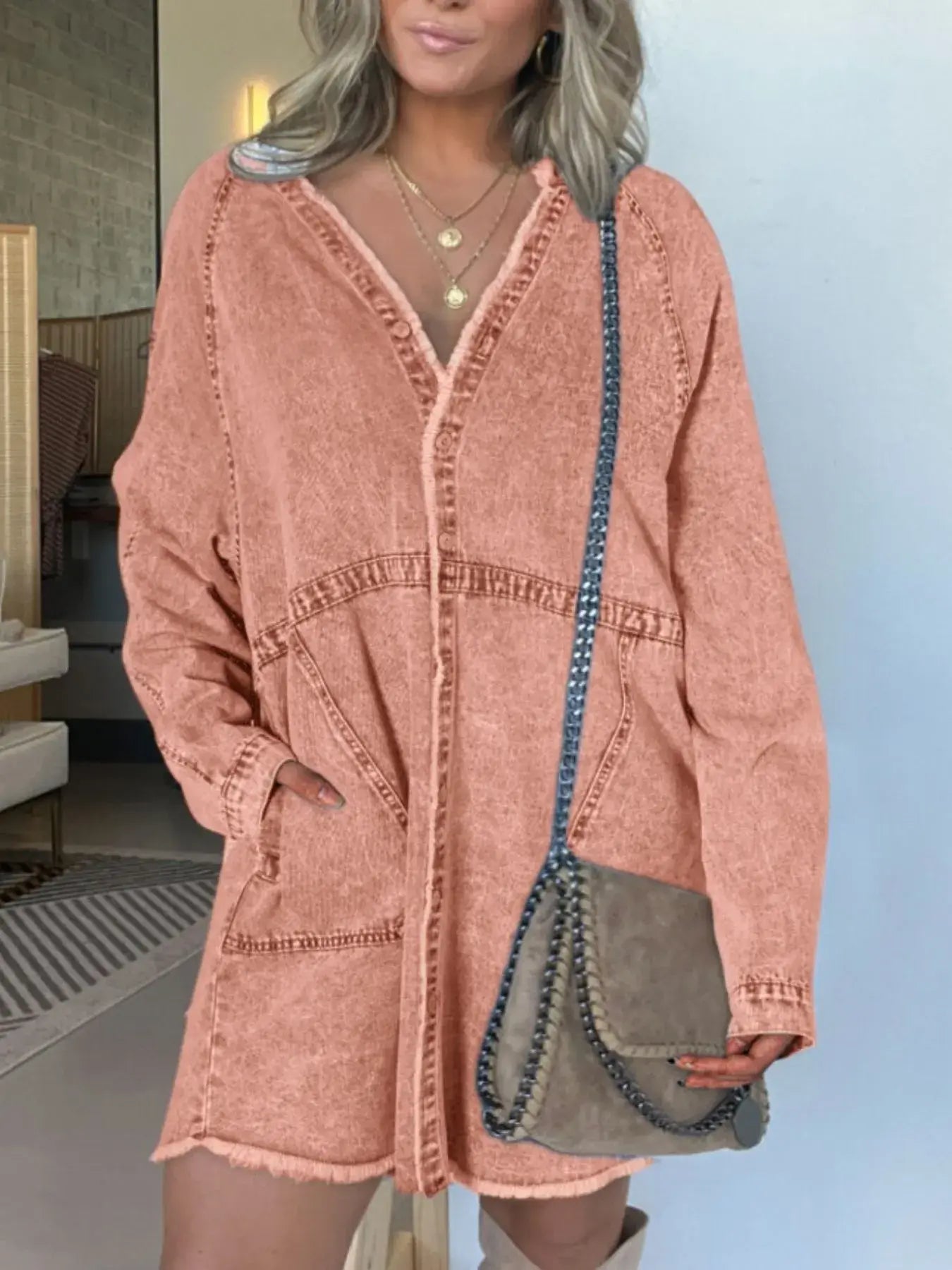 Model wearing a stylish oversized button-front denim dress in a peach color, paired with a chic handbag.