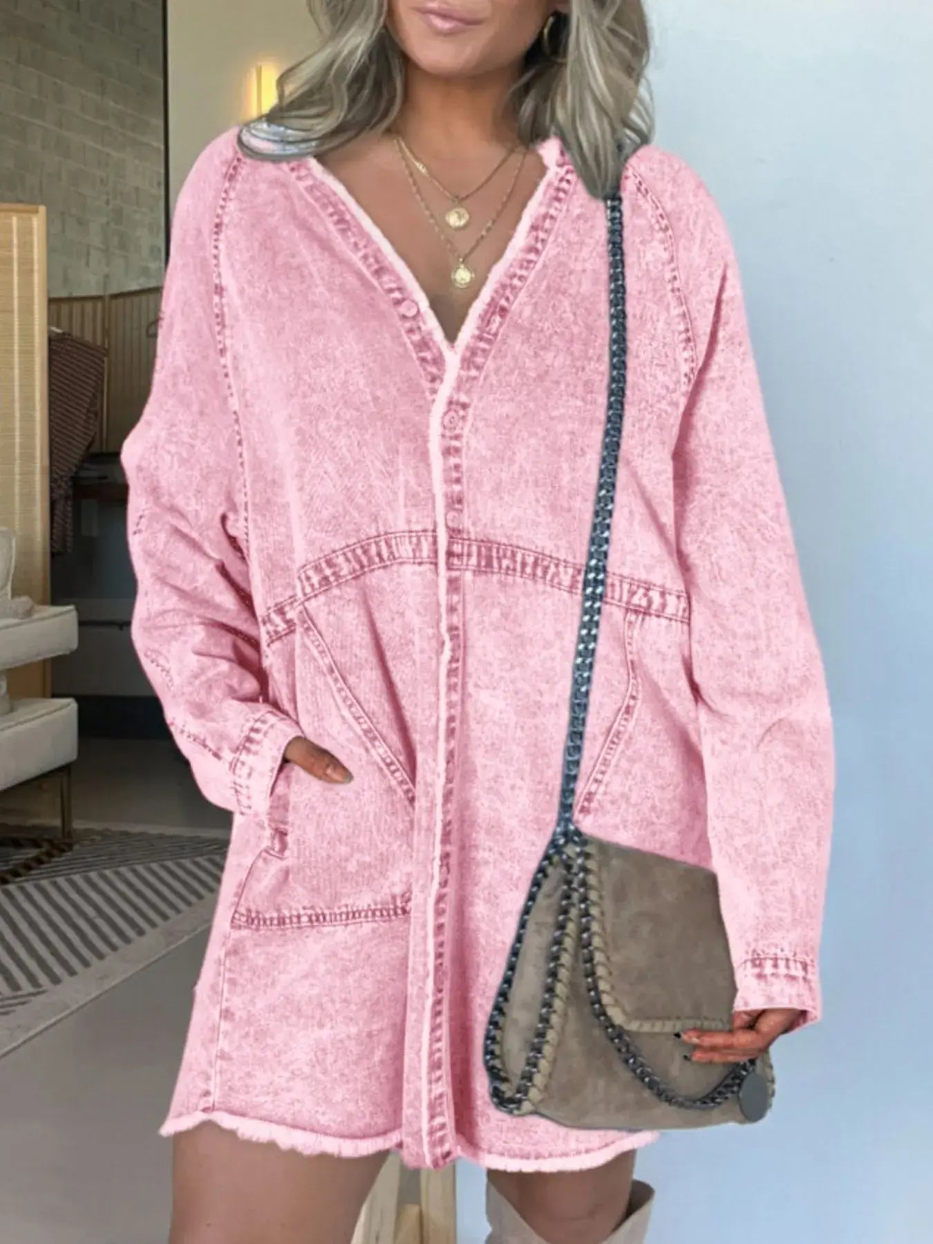 Woman modeling a pink button-front denim shirt dress with pockets, paired with a stylish crossbody bag.