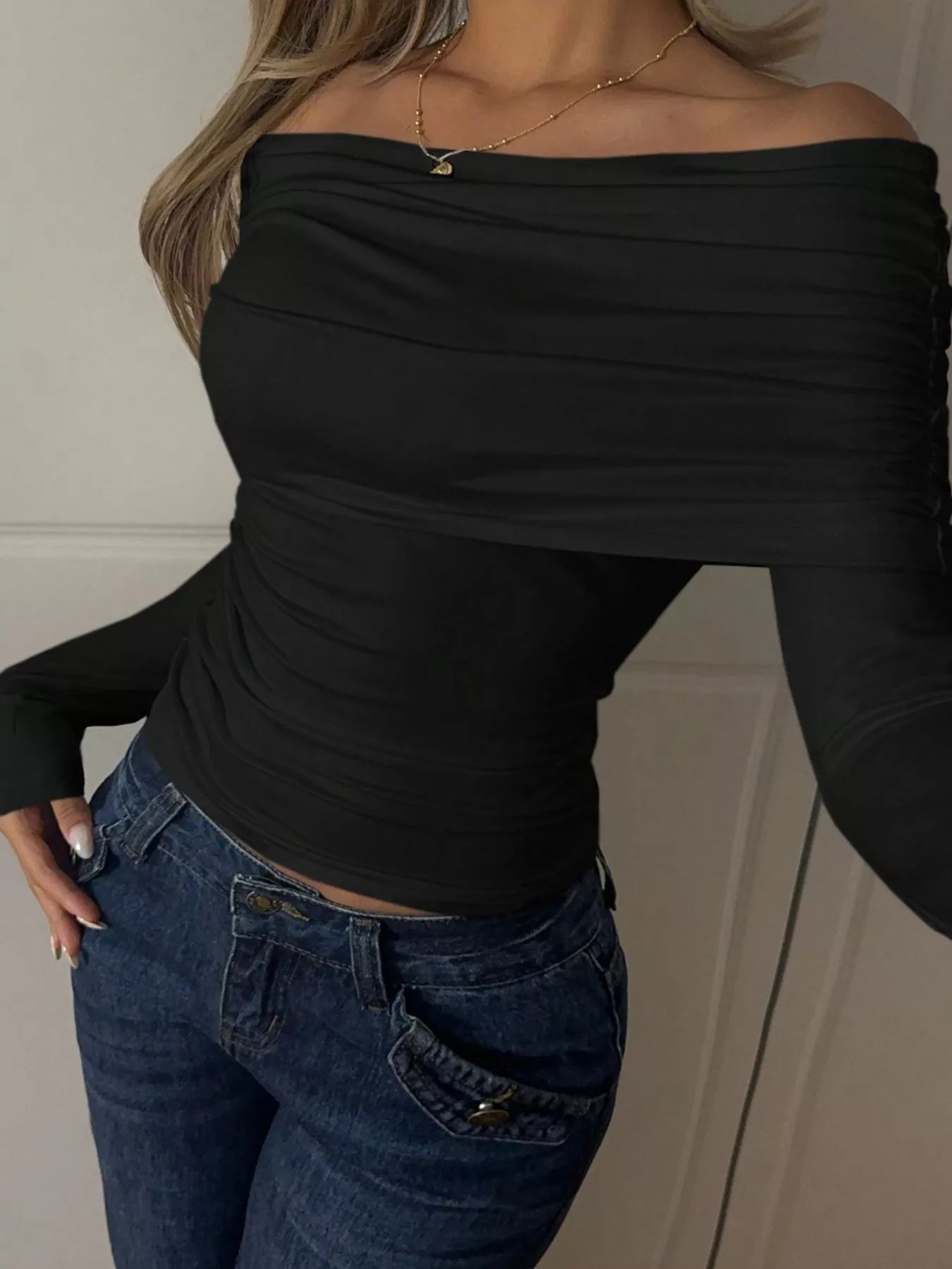 Off-Shoulder Ruched Long Sleeve T-Shirt in black worn with jeans, showcasing trendy design and slightly stretchy material.
