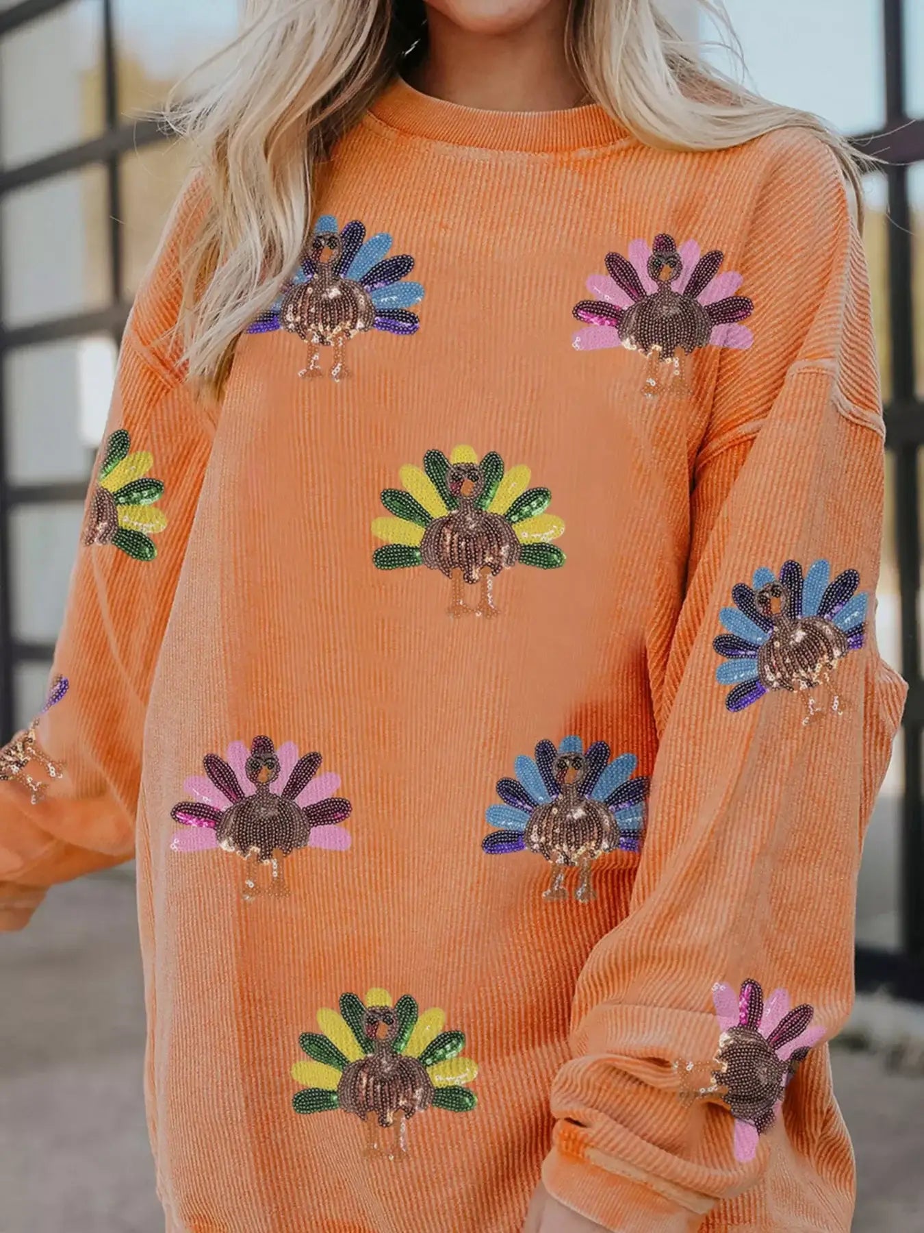 Turkey Graphic Corded Baggy Sweatshirt with colorful turkey graphics on an orange background.