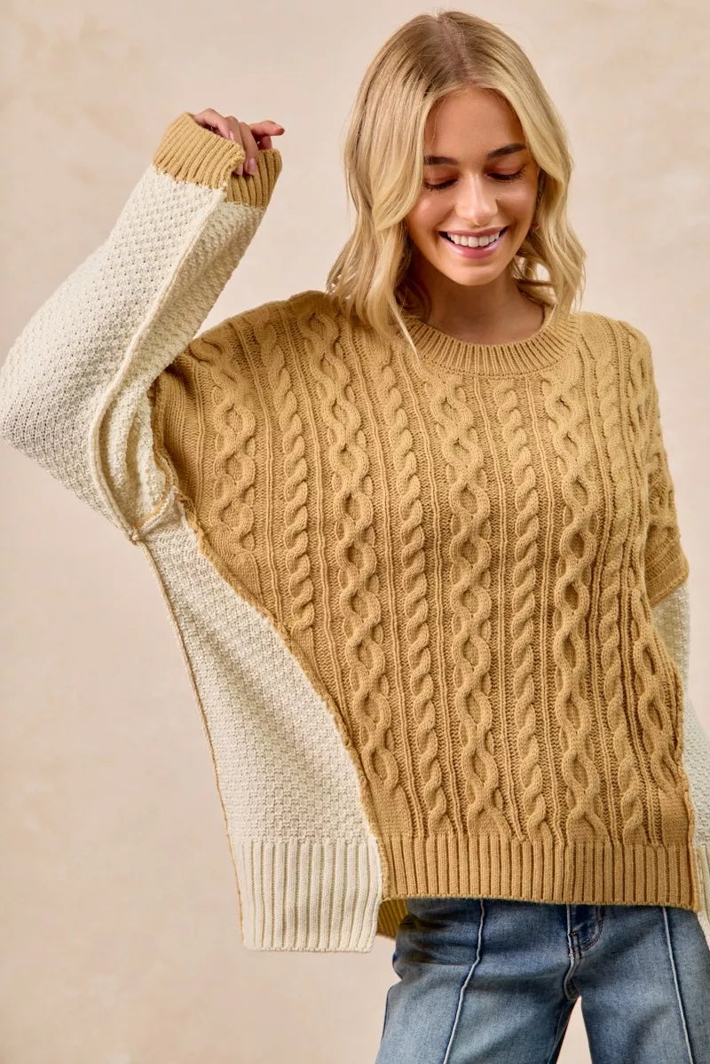 Model wearing BiBi Cable Knit Hacci Combo Sweater with uneven hem, showcasing cozy texture in warm colors.