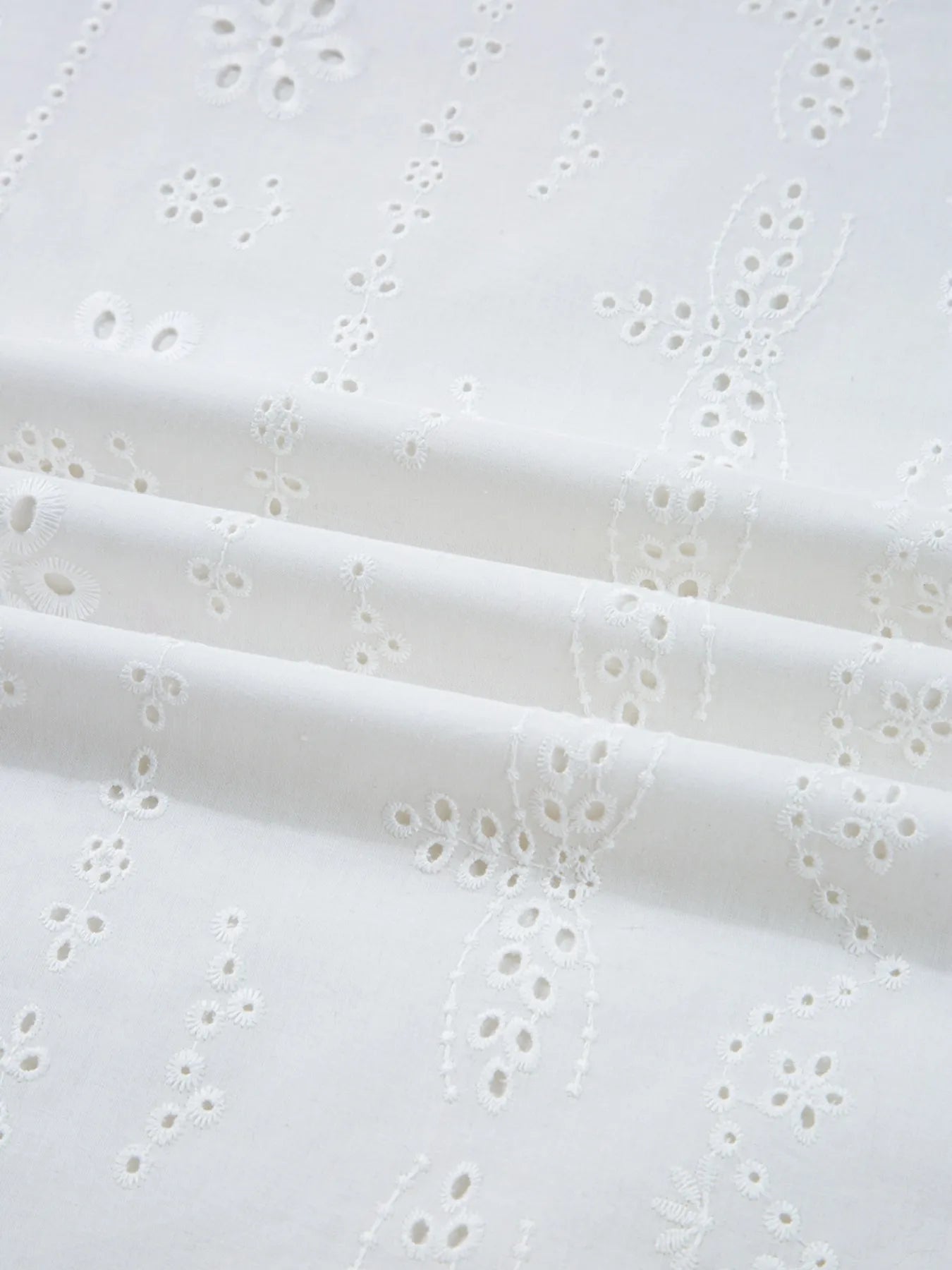 Close-up of delicate eyelet fabric for Eyelet Long Sleeve Blouse with Elastic Cuffs, showcasing intricate embroidery details.