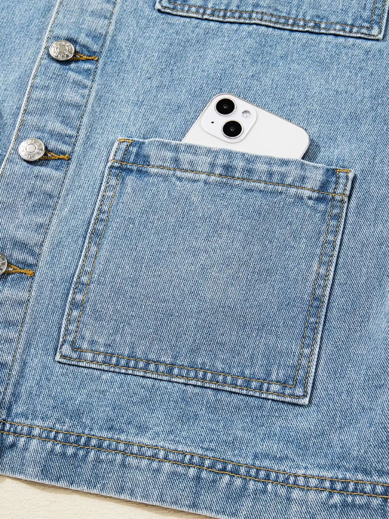 Close-up of patched pocket on denim jacket with a smartphone inside, showcasing functional design.