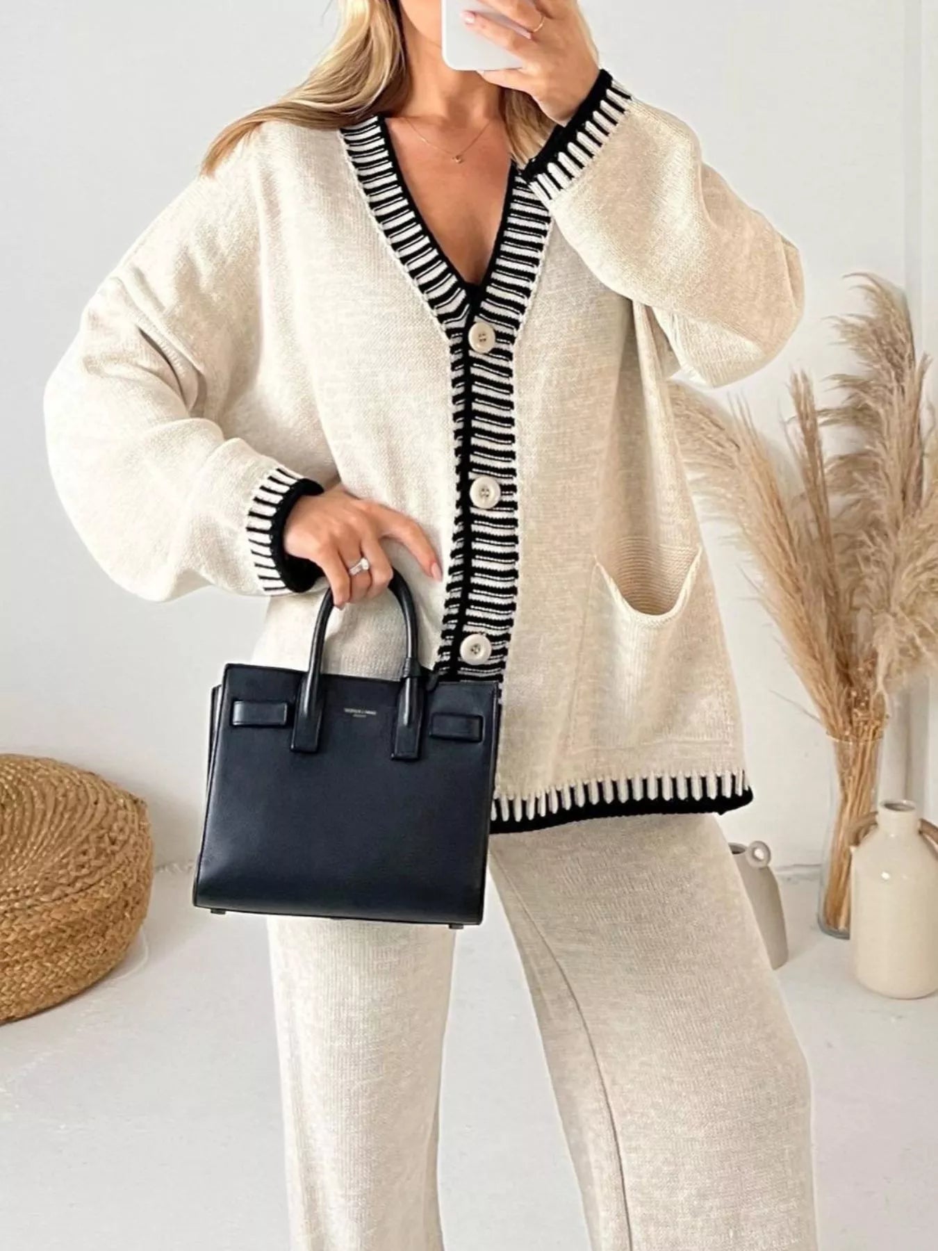 Model wearing Button Up V-Neck Cardigan and Pants Sweater Set while holding a black handbag, showcasing style and comfort.
