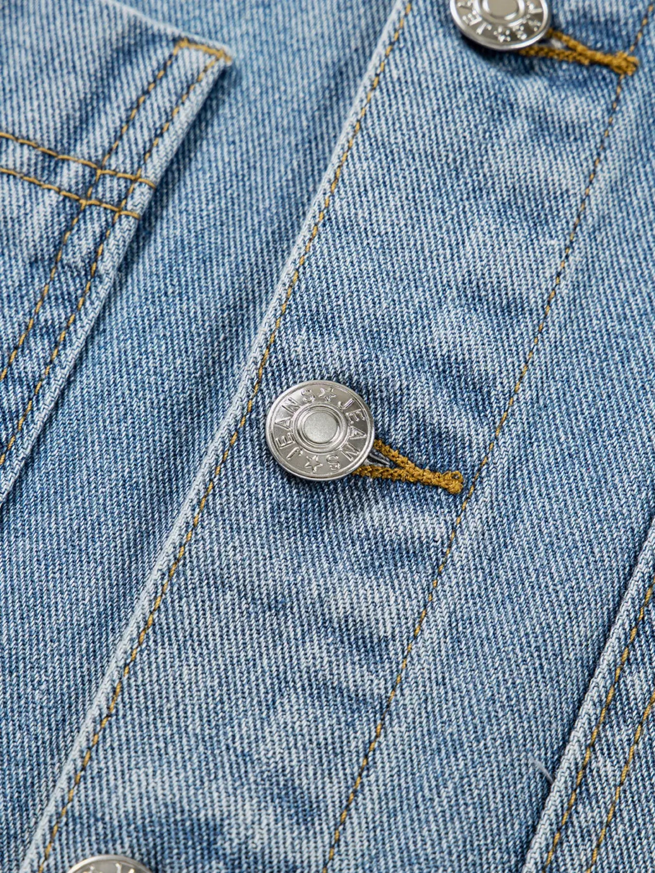 Close-up of the silver buttons and textured fabric on a denim jacket, showcasing its quality details.