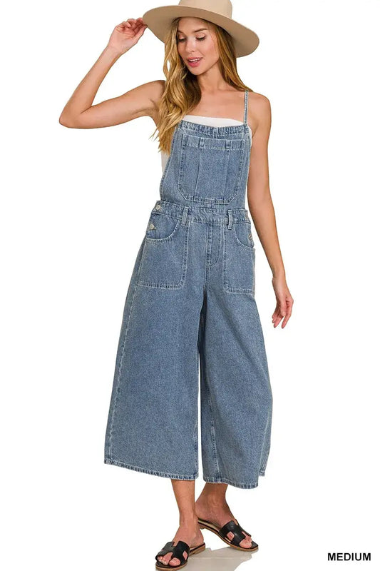 Model wearing Zenana Denim Wide Leg Overalls in medium wash, styled with a straw hat and sandals, showcasing casual chic.