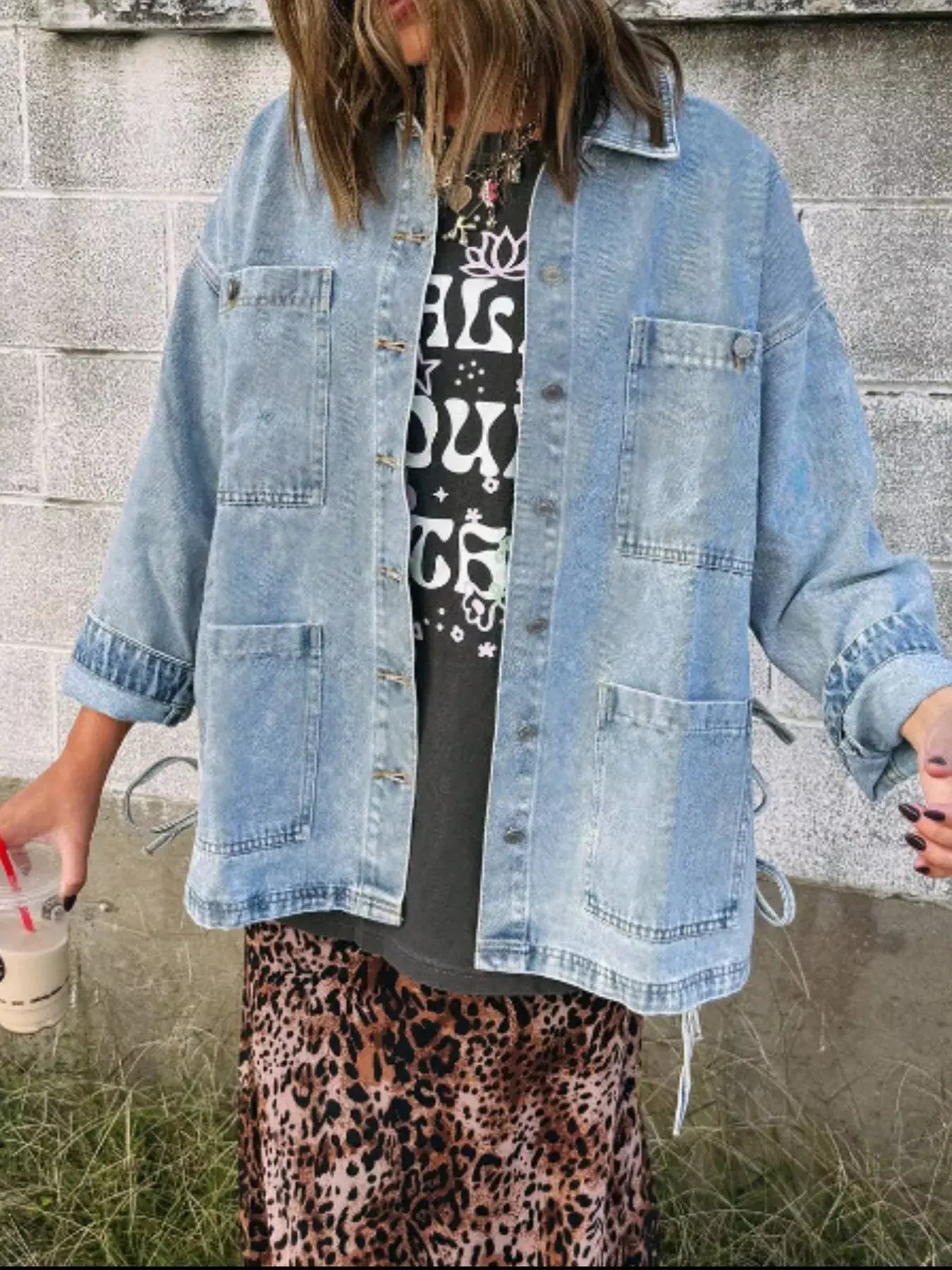 Woman wearing a patched pockets side tie denim jacket with a graphic tee and leopard print skirt.