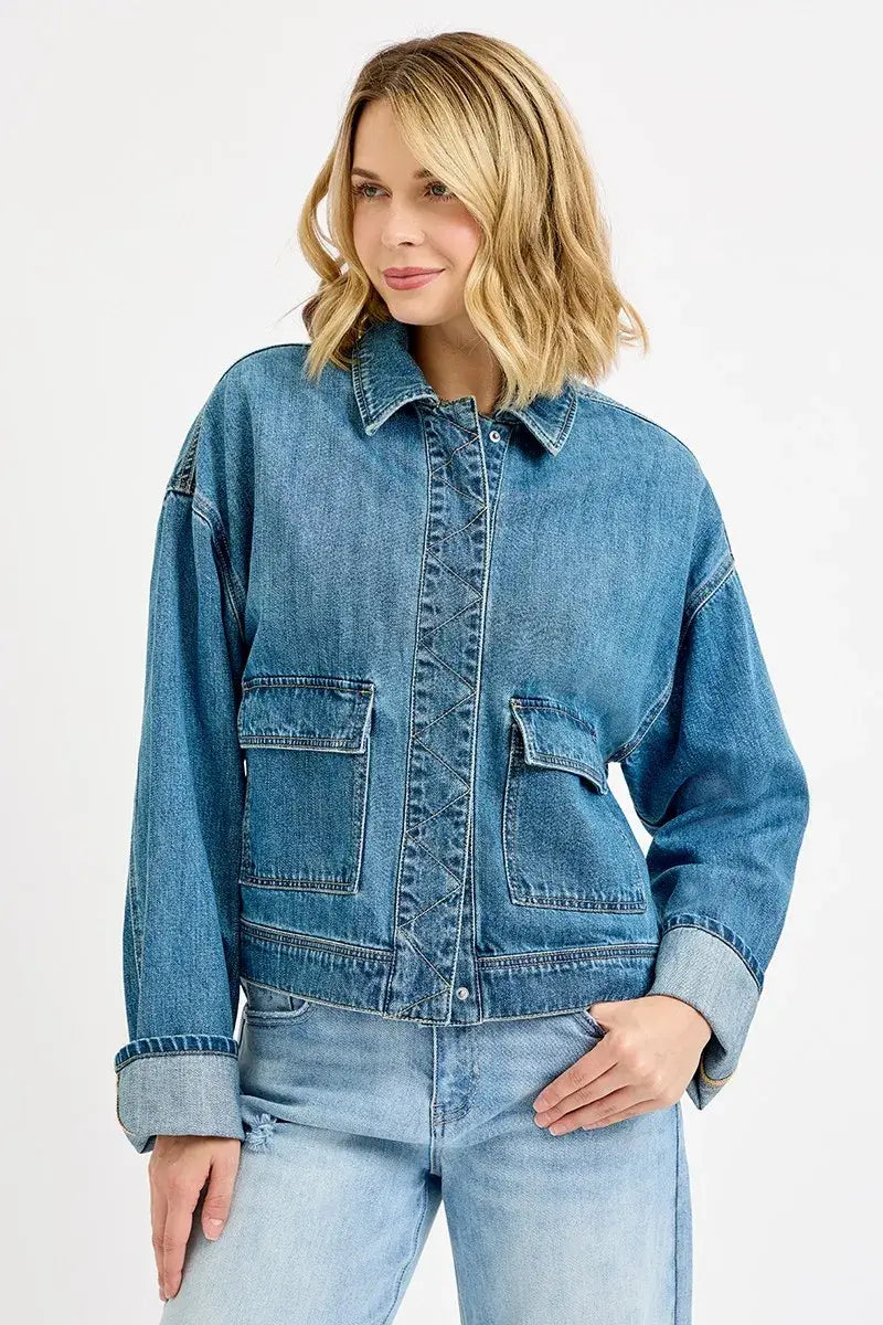 Woman wearing RISEN oversized cargo denim jacket with cuffed sleeves and pockets, styled for a casual look.