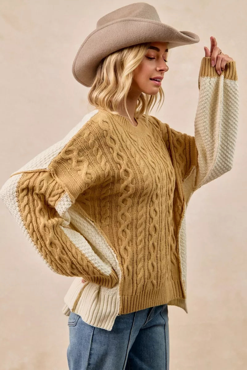 BiBi Cable Knit Hacci Combo Sweater styled with hat, showcasing unique cable knit design and uneven hem.