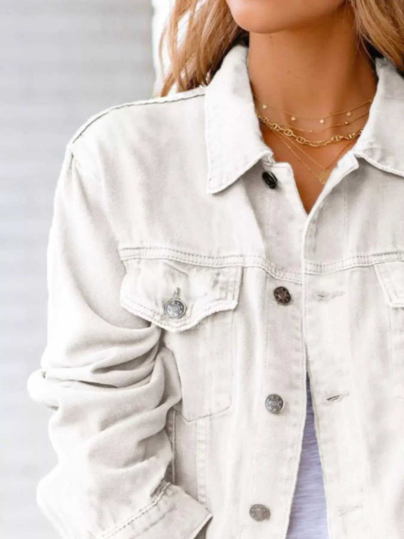 Women's button up long sleeve denim jacket in light wash, featuring front pockets and a stylish collar.