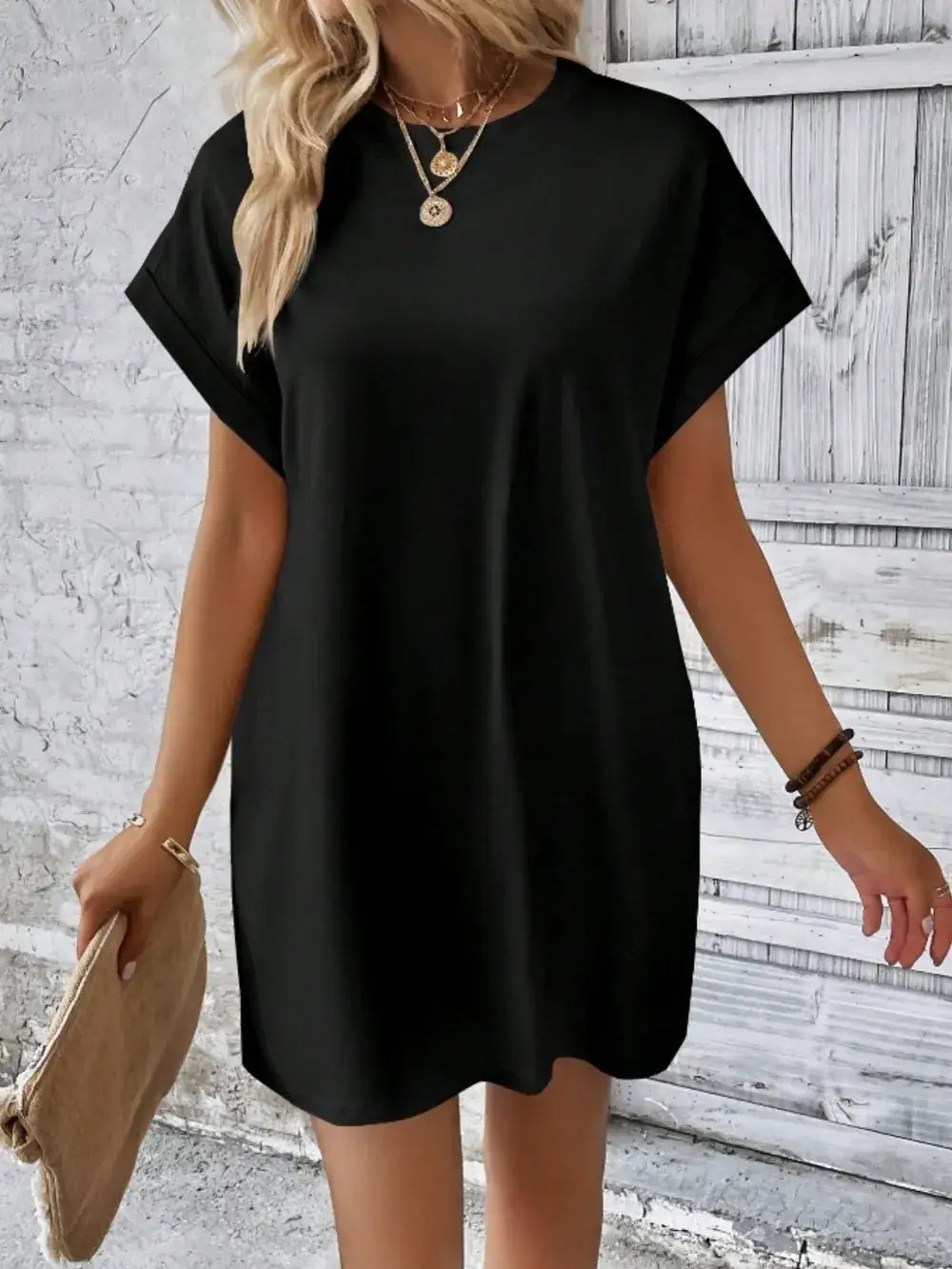 Casual pocketed round neck black short sleeve dress styled with accessories against a textured background.