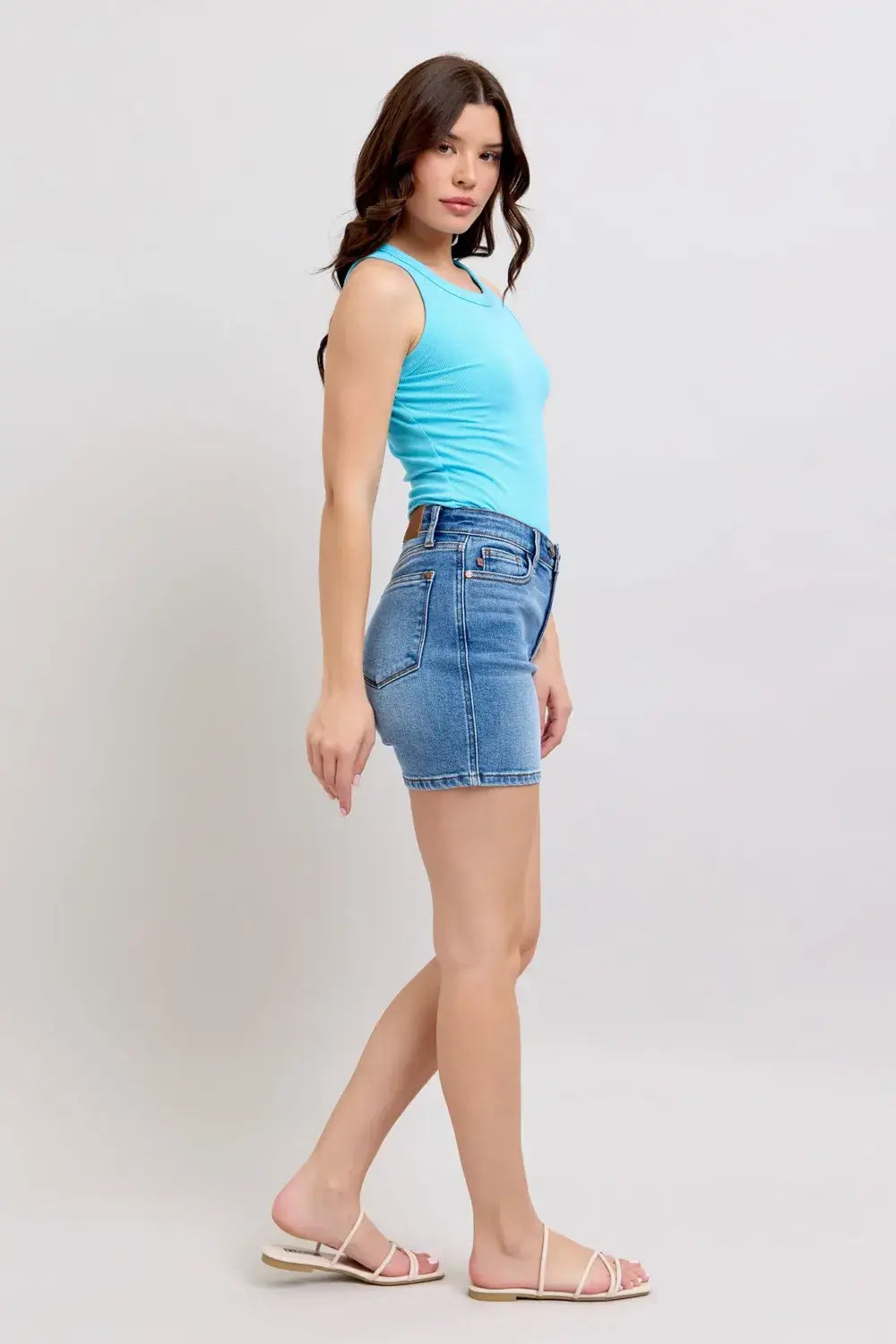 Model wearing Judy Blue Plus Size Denim Shorts with blue tank top and sandals, showcasing pockets and flattering fit.