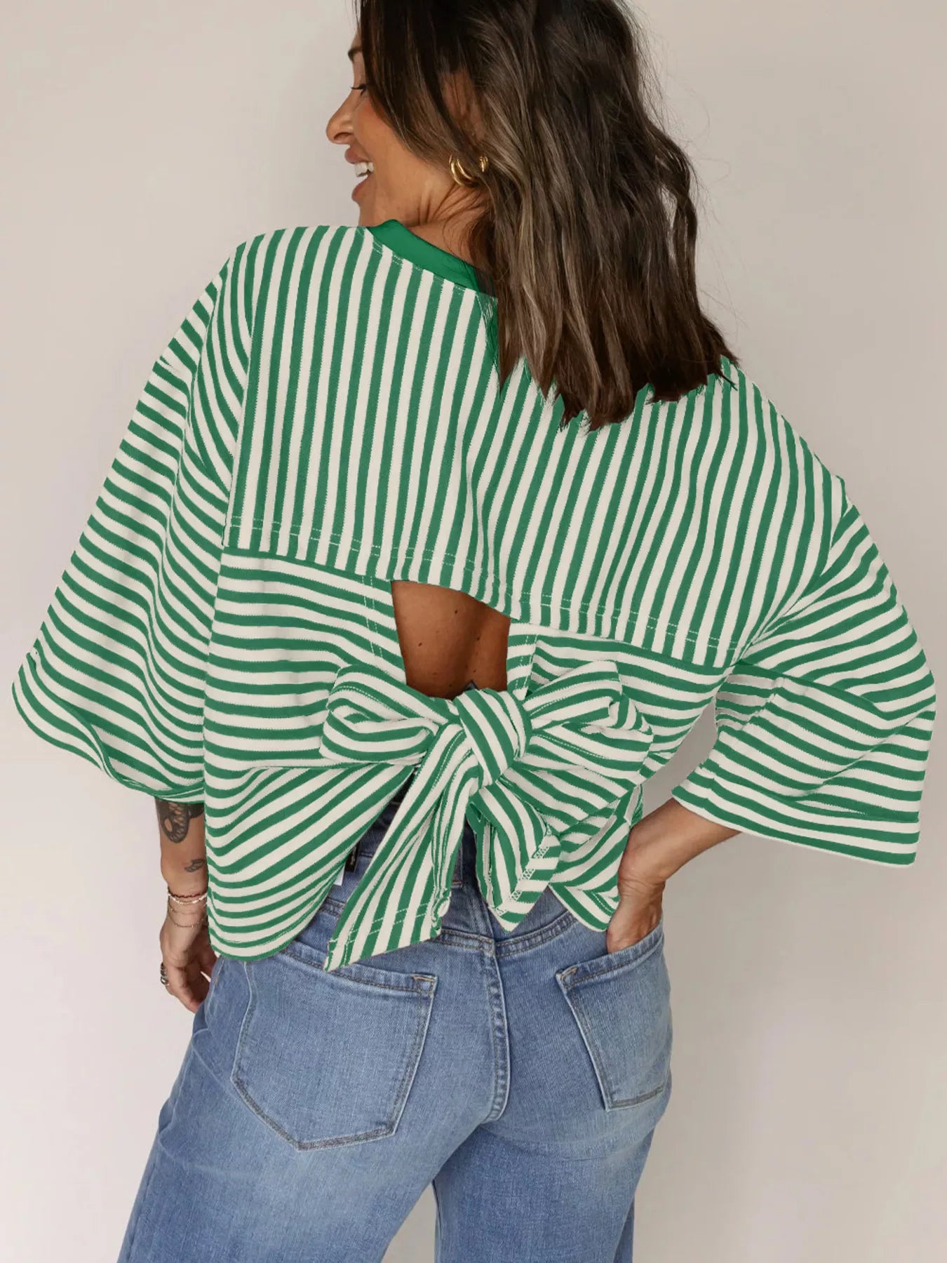 Striped Back Bow Tie T-Shirt in green and white stripes worn with denim jeans, showcasing the oversized bow detail.