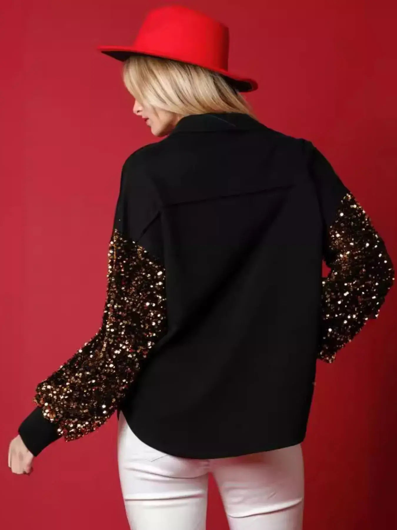Model wearing a Christmas Santa Sequin Long Sleeve Shirt with shiny sleeves, complemented by a red hat against a festive backdrop.