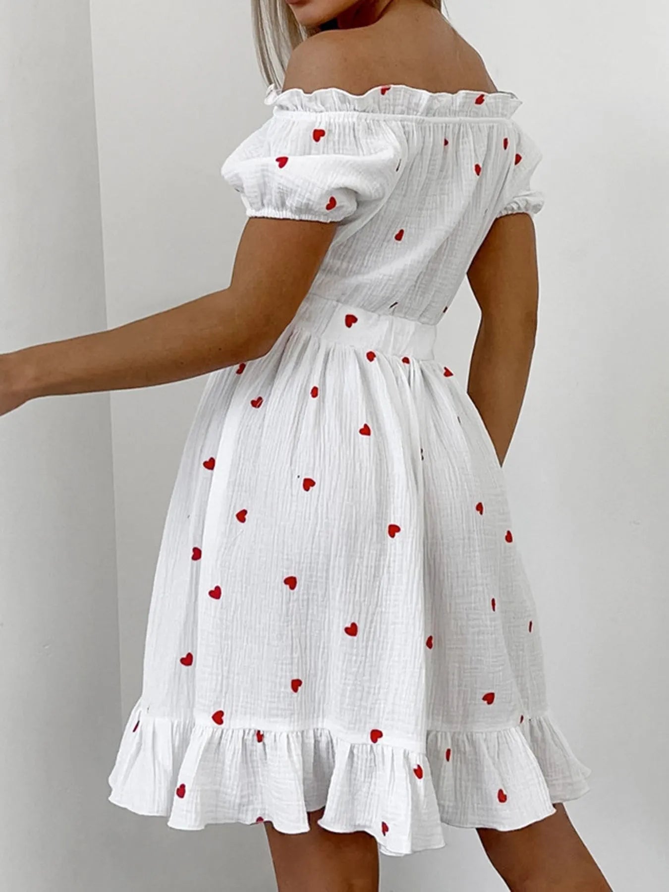 Heart Printed Off-Shoulder Ruffle Mini Dress showcasing a woman in a white dress with red hearts and a frill hem.