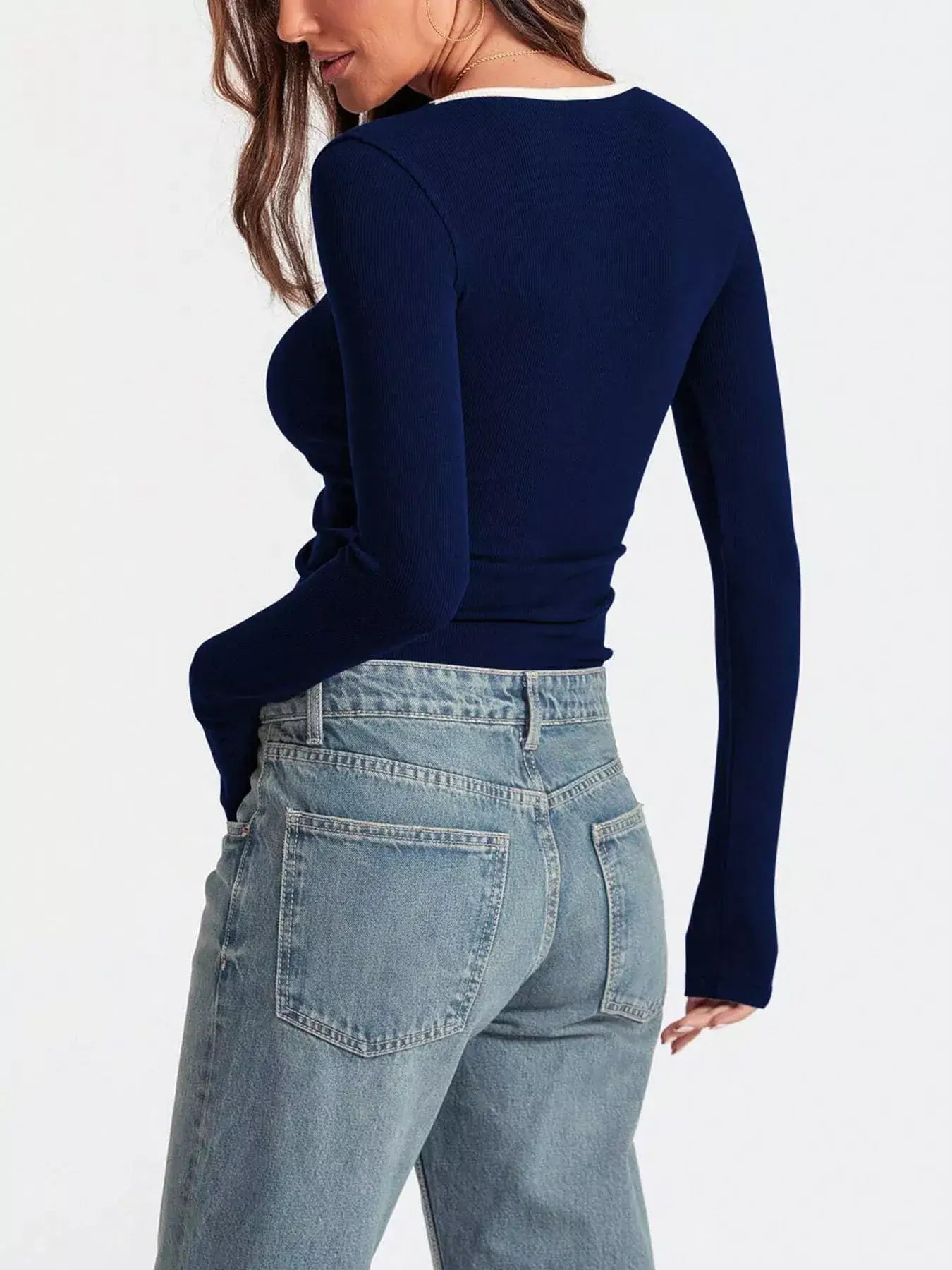 Back view of a woman wearing a navy scoop neck long sleeve t-shirt paired with high-waisted jeans.