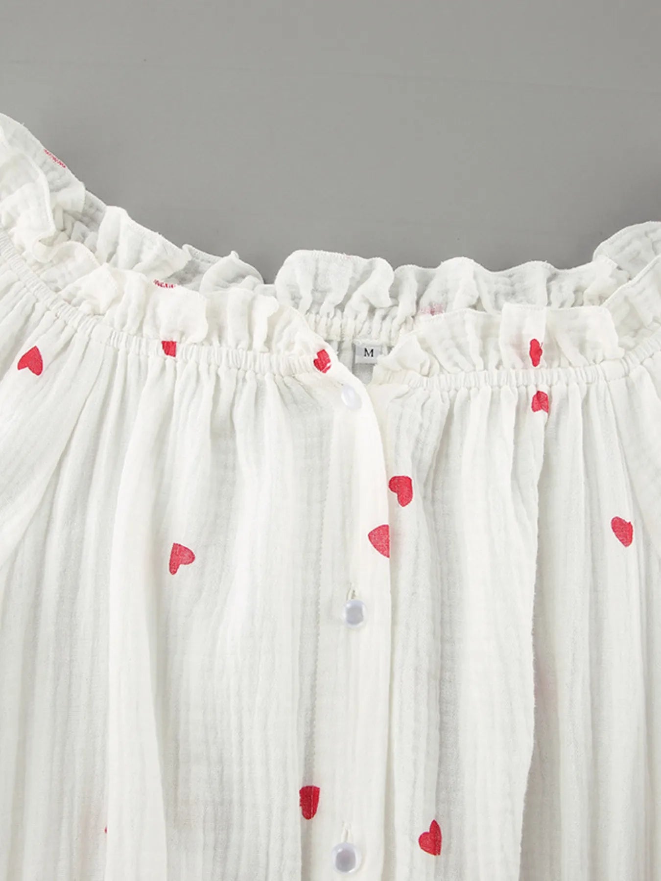 Heart Printed Off-Shoulder Ruffle Mini Dress featuring heart prints and button details on a light fabric.