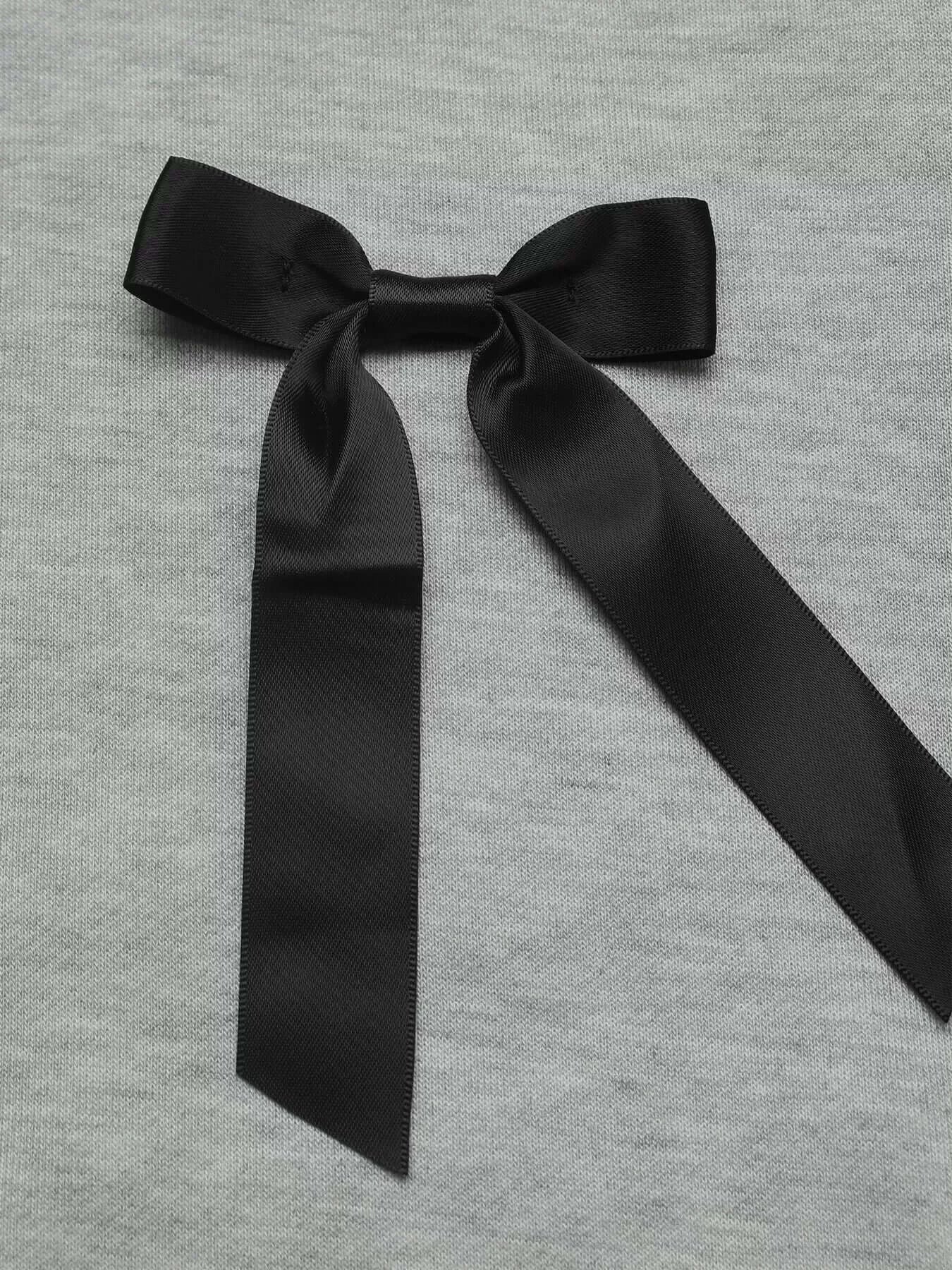 Close-up of a black bow detail on a gray Bow Detail Round Neck Sweatshirt, adding a feminine touch.