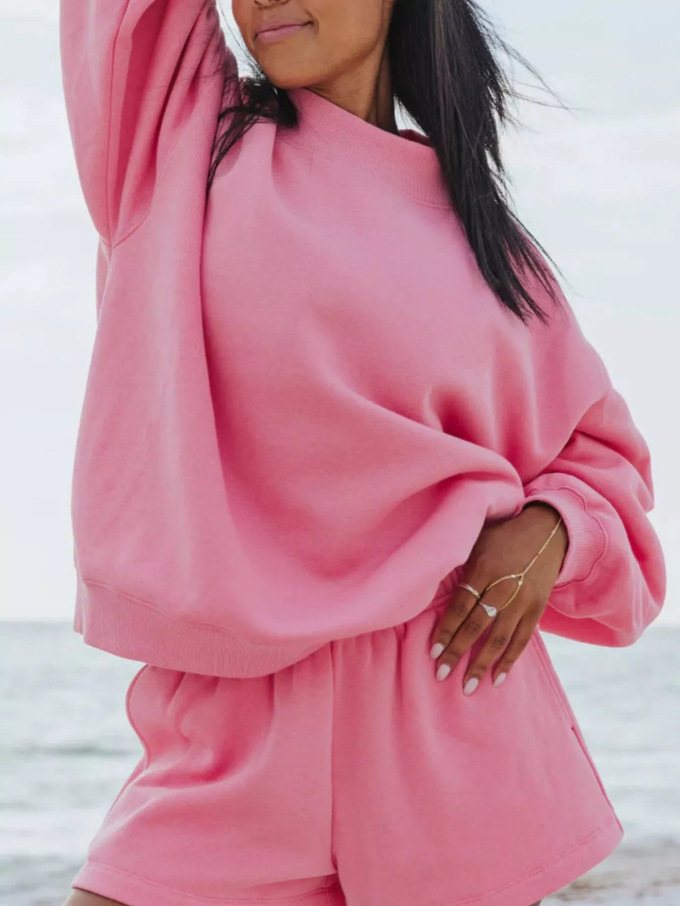 Relaxed Fit Round Neck Sweatshirt and Shorts Set in pink worn by a model at the beach, casual style with a relaxed fit.