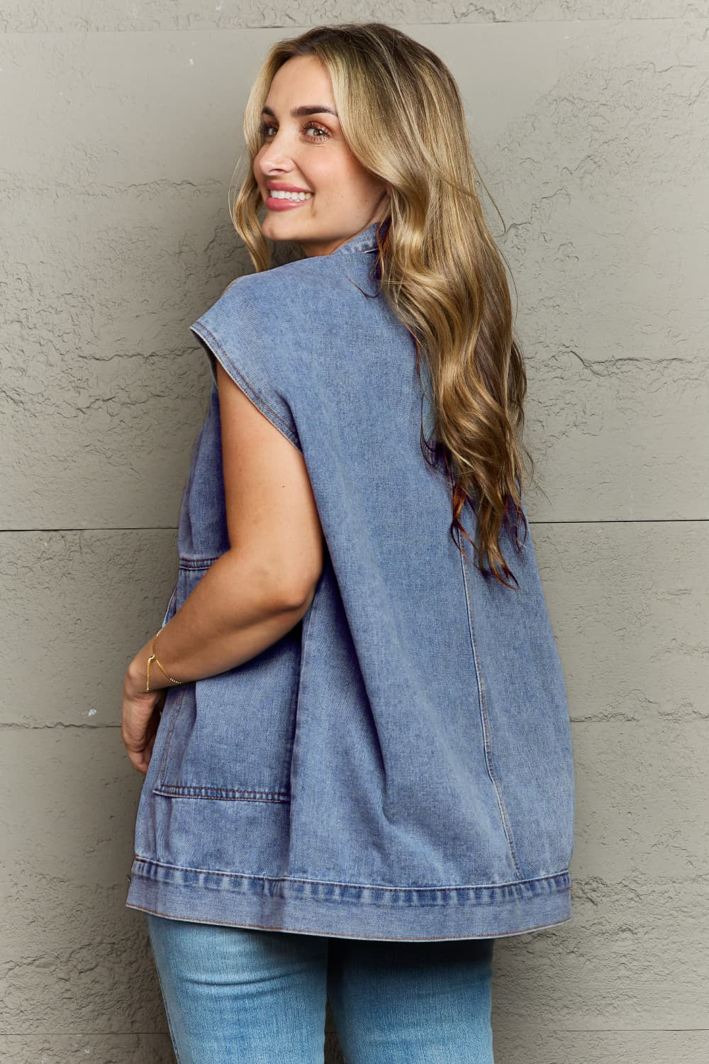 Collared Neck Sleeveless Denim Top with Pockets worn by a woman, showcasing back view against a textured wall.