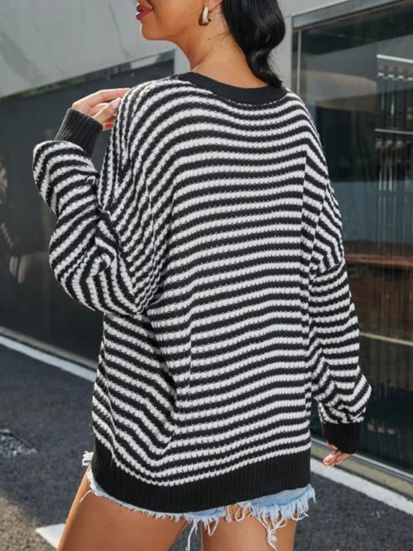 Woman wearing a Striped Round Neck Drop Shoulder Sweater with an oversized fit, paired with denim shorts.