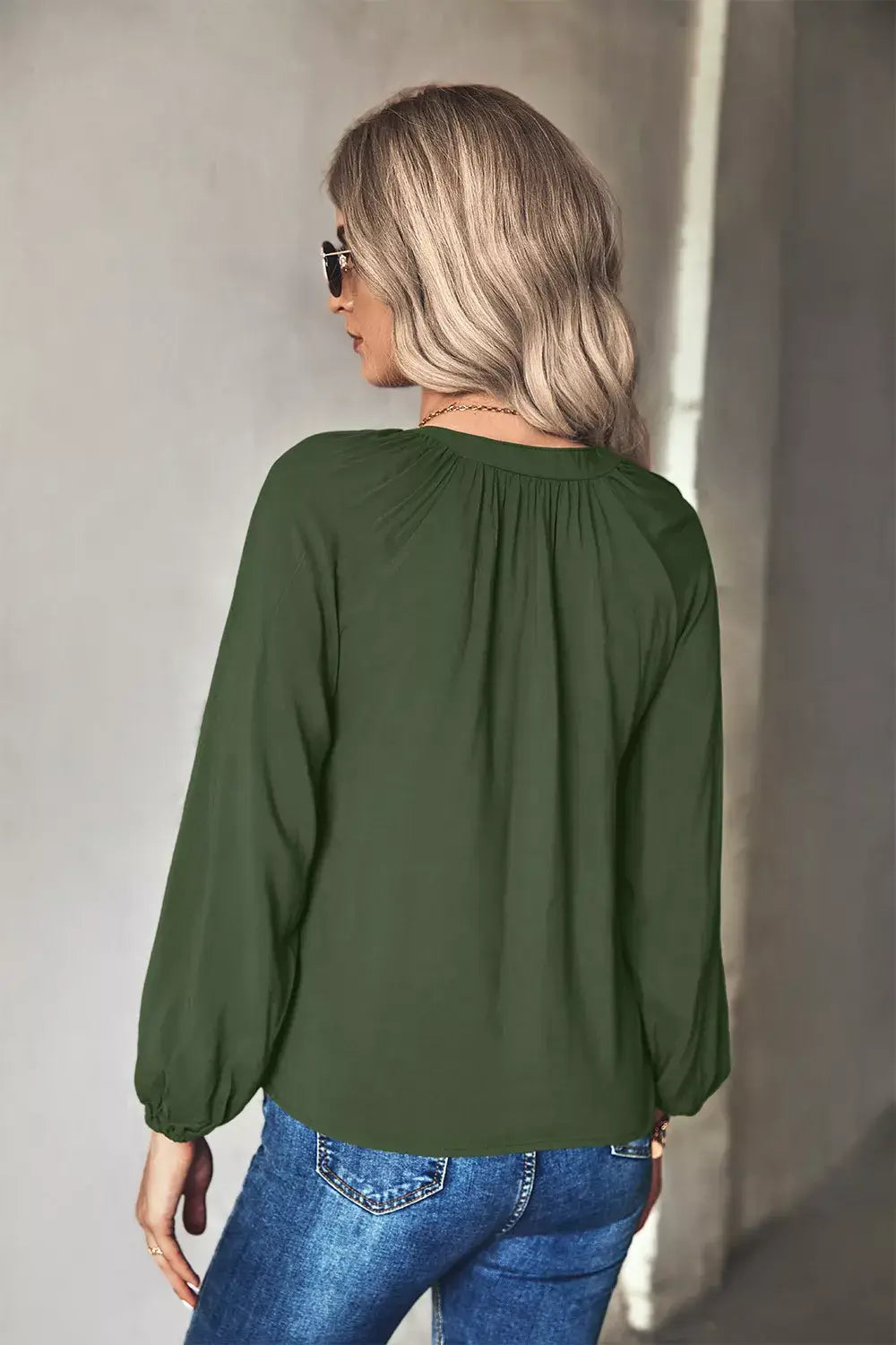 Back view of a woman wearing a tie neck long sleeve blouse in green, perfect for office and evening wear.