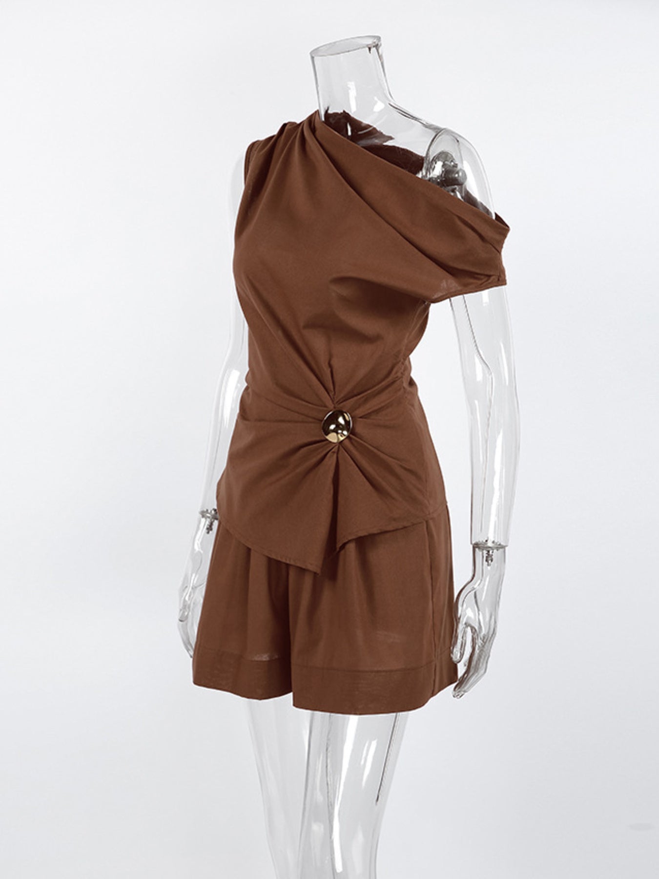 Stylish one shoulder top and shorts set featuring a ruched design and asymmetrical look on a clear mannequin.